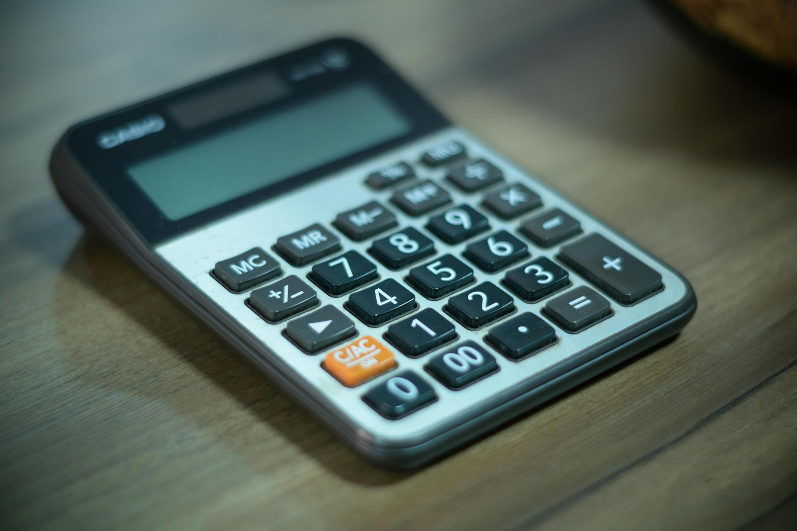 A close‑up of a Casio scientific calculator with buttons and display rests on a brown wooden surface.