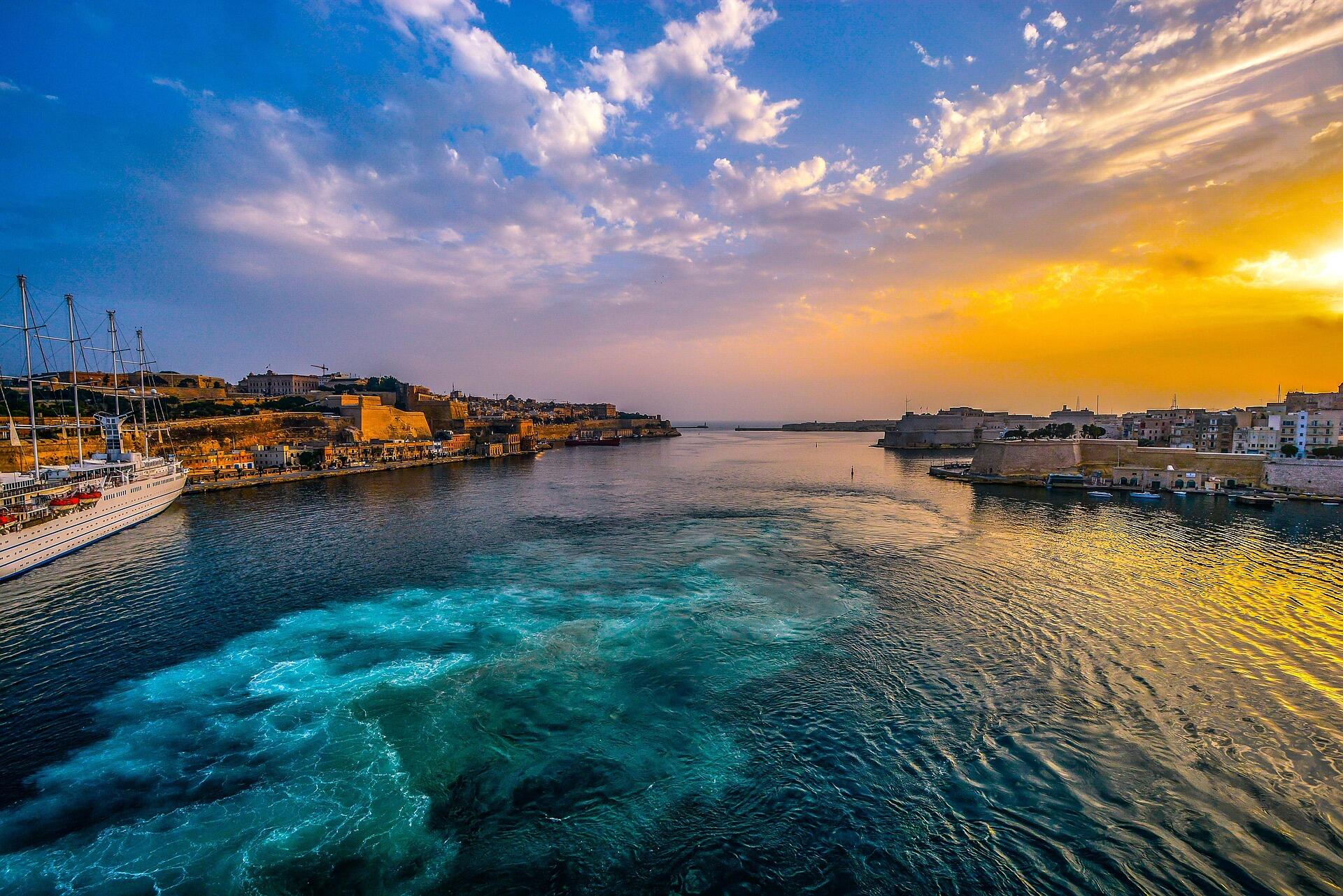 Sunset view of Malta’s harbor between Valletta and Sliema with yachts and historic waterfront.