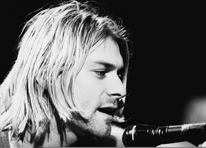 Kurt Cobain performing on stage with his guitar during a 1990s Nirvana concert.