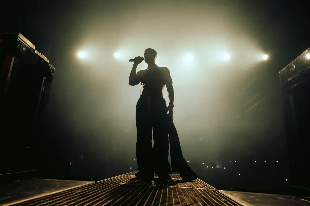 Maltese singer performing live on stage under a dramatic spotlight during a powerful vocal moment.