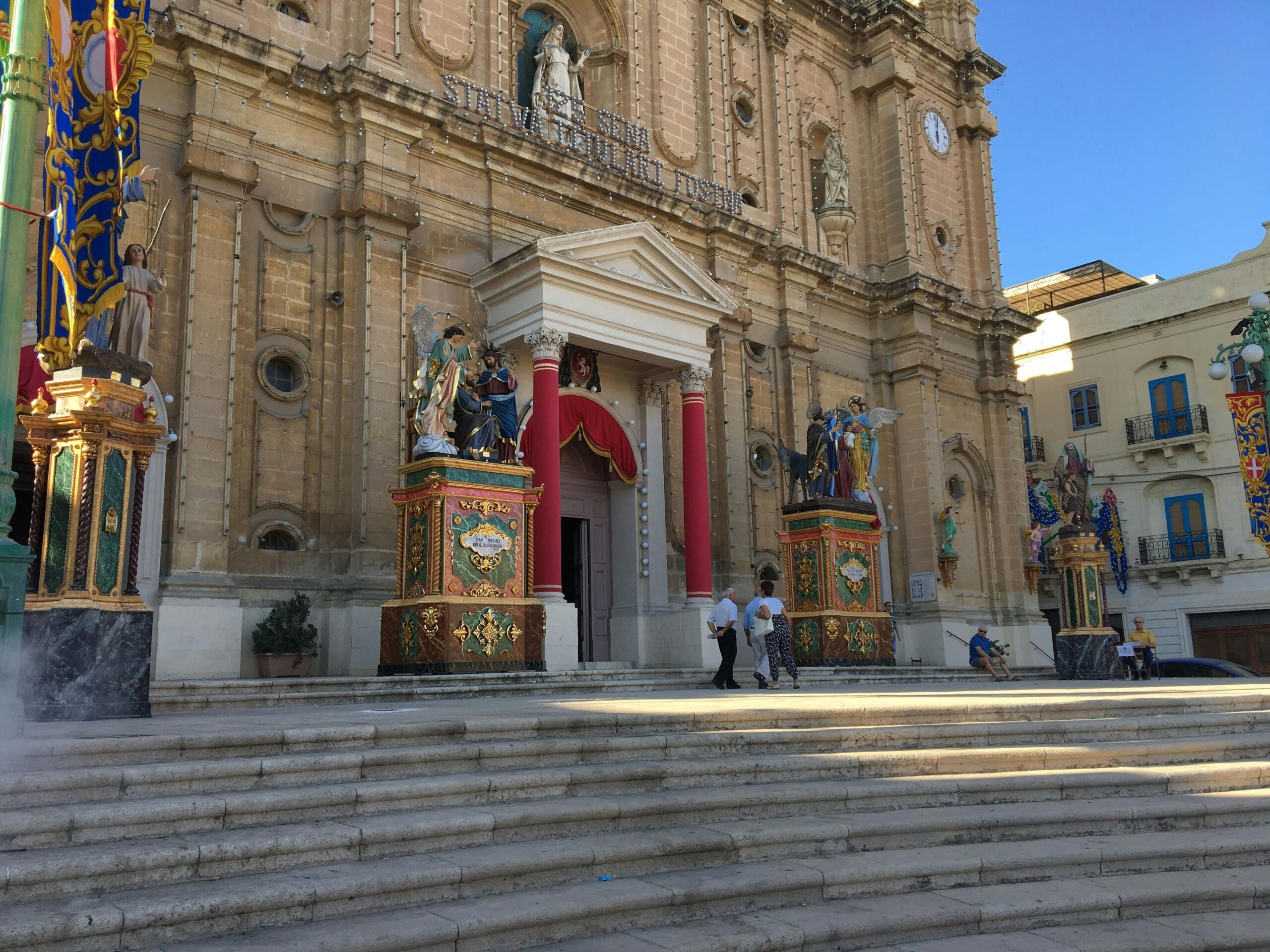 Decorated church facade in Malta during Holy Week with religious statues outside the entrance
