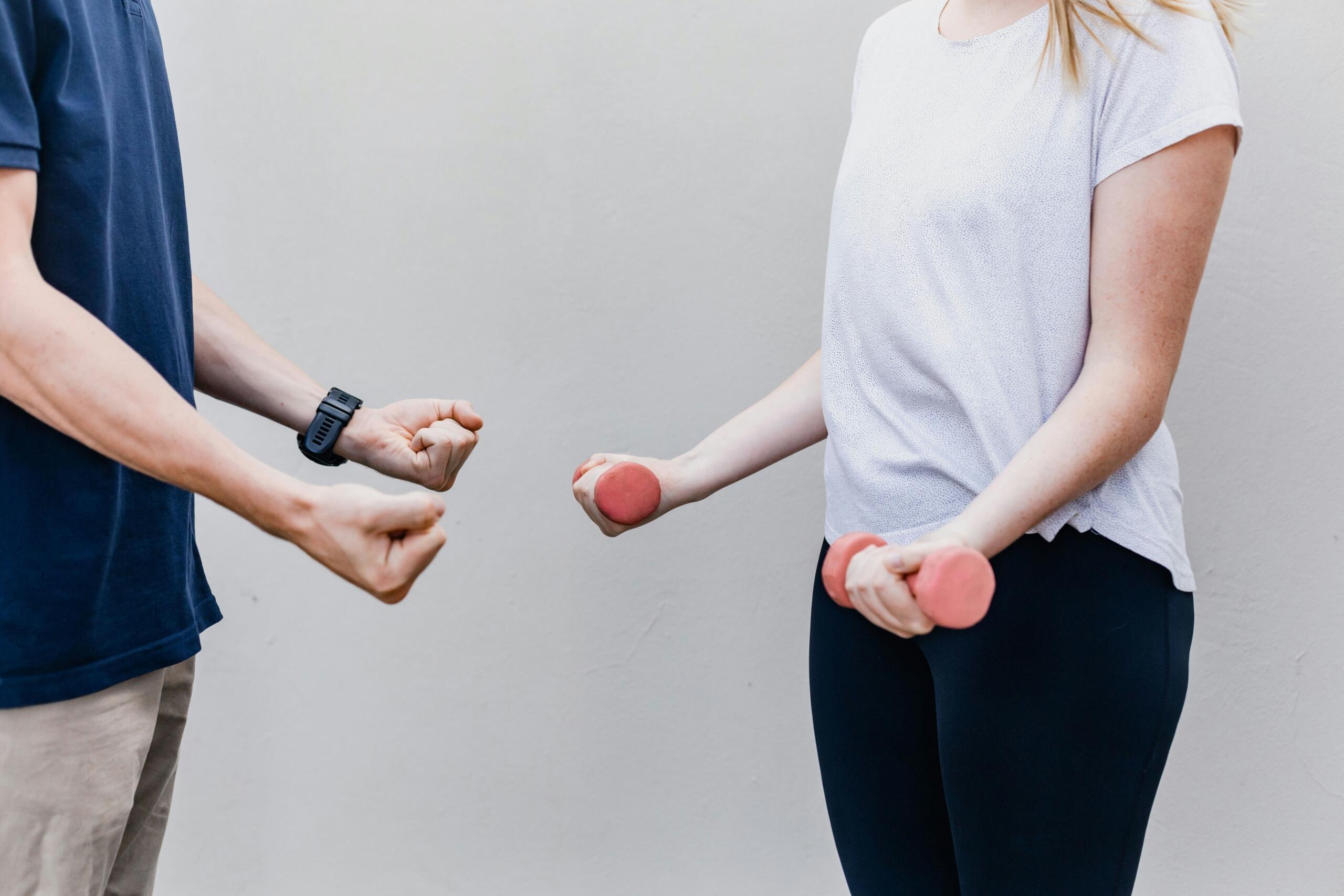 Man and woman facing each other while holding dumbbells