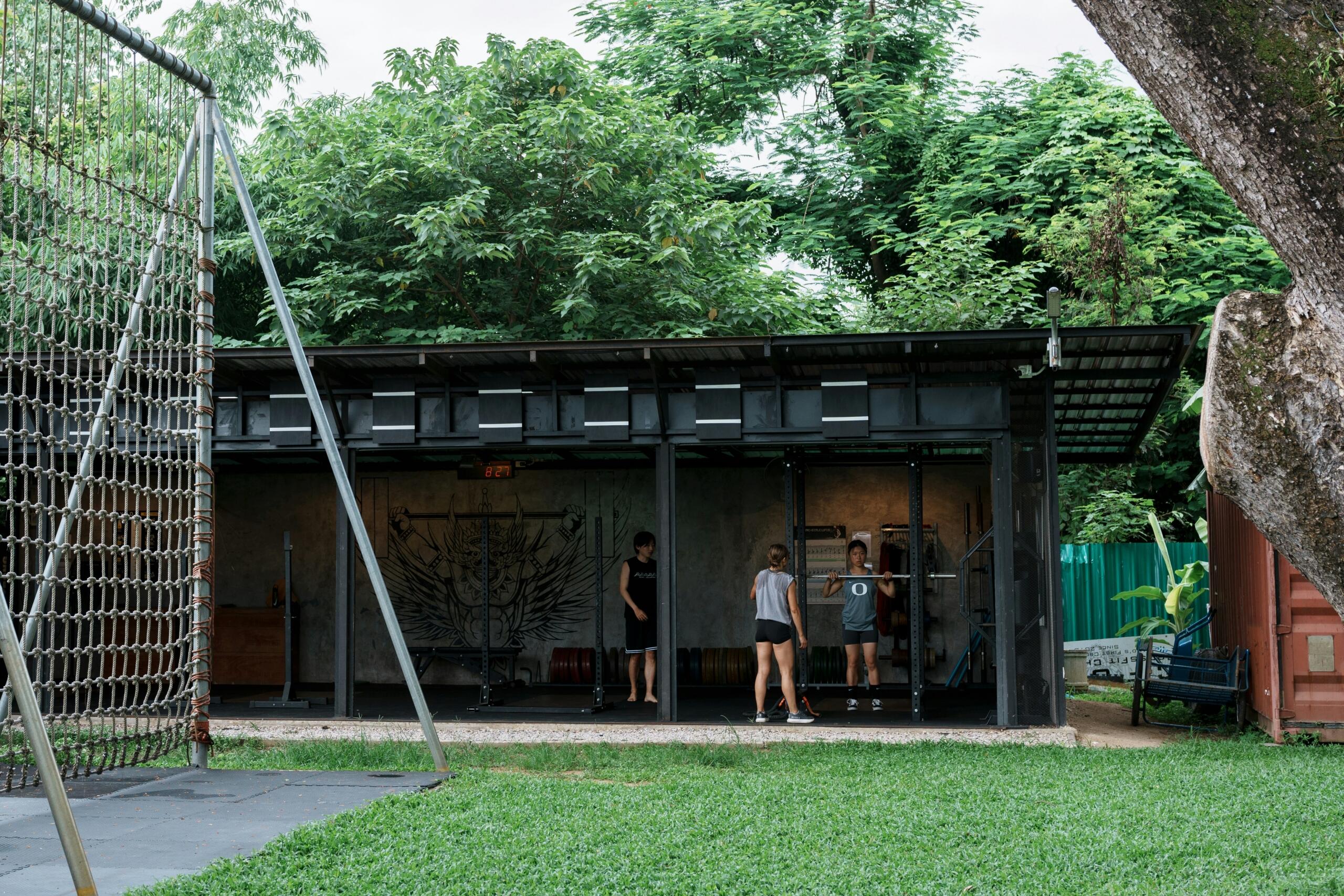 Outdoor training equipment stands on green turf beside a modern building.