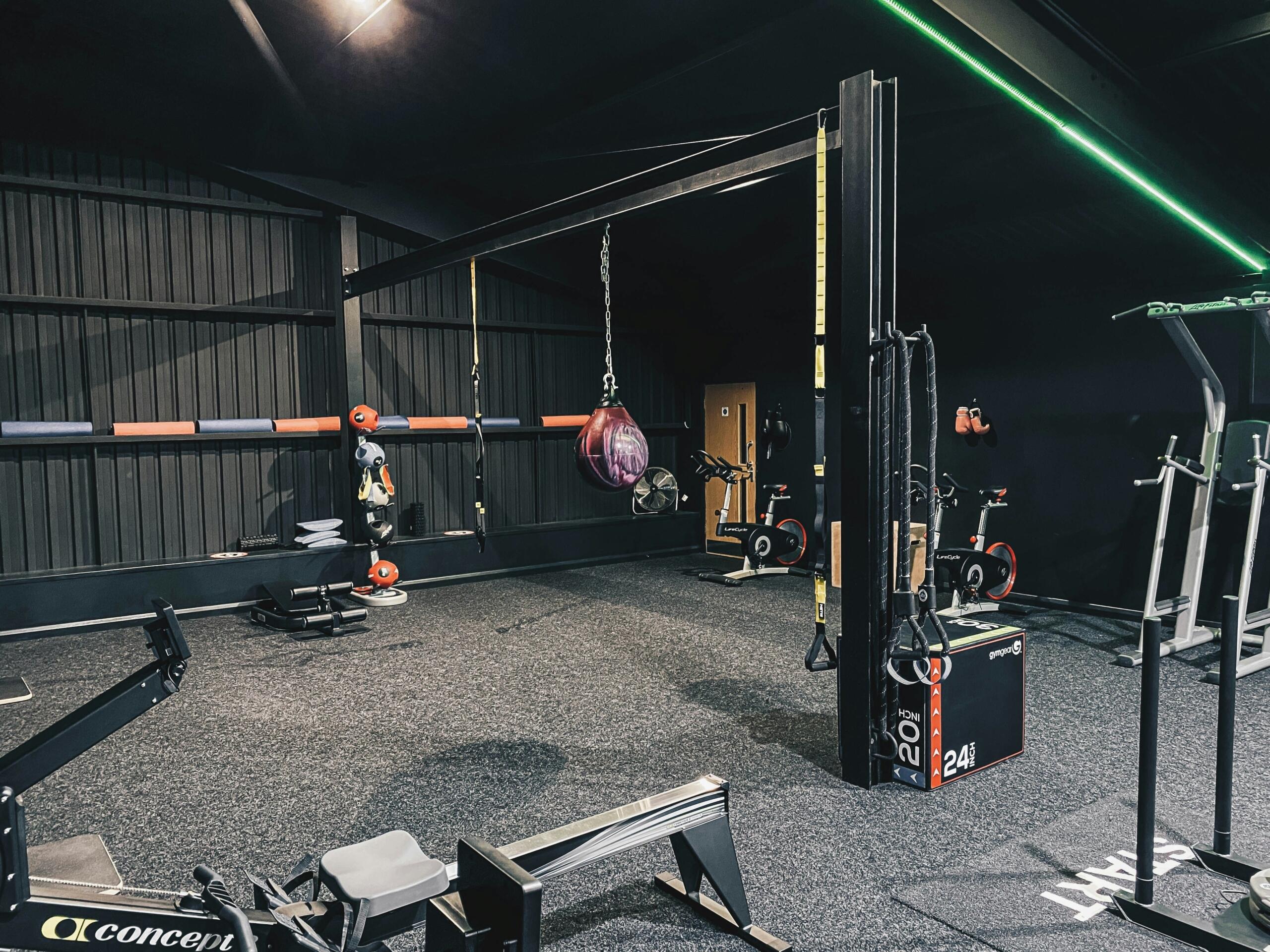 A gym floor is filled with barbells, benches, racks, and other strength equipment.