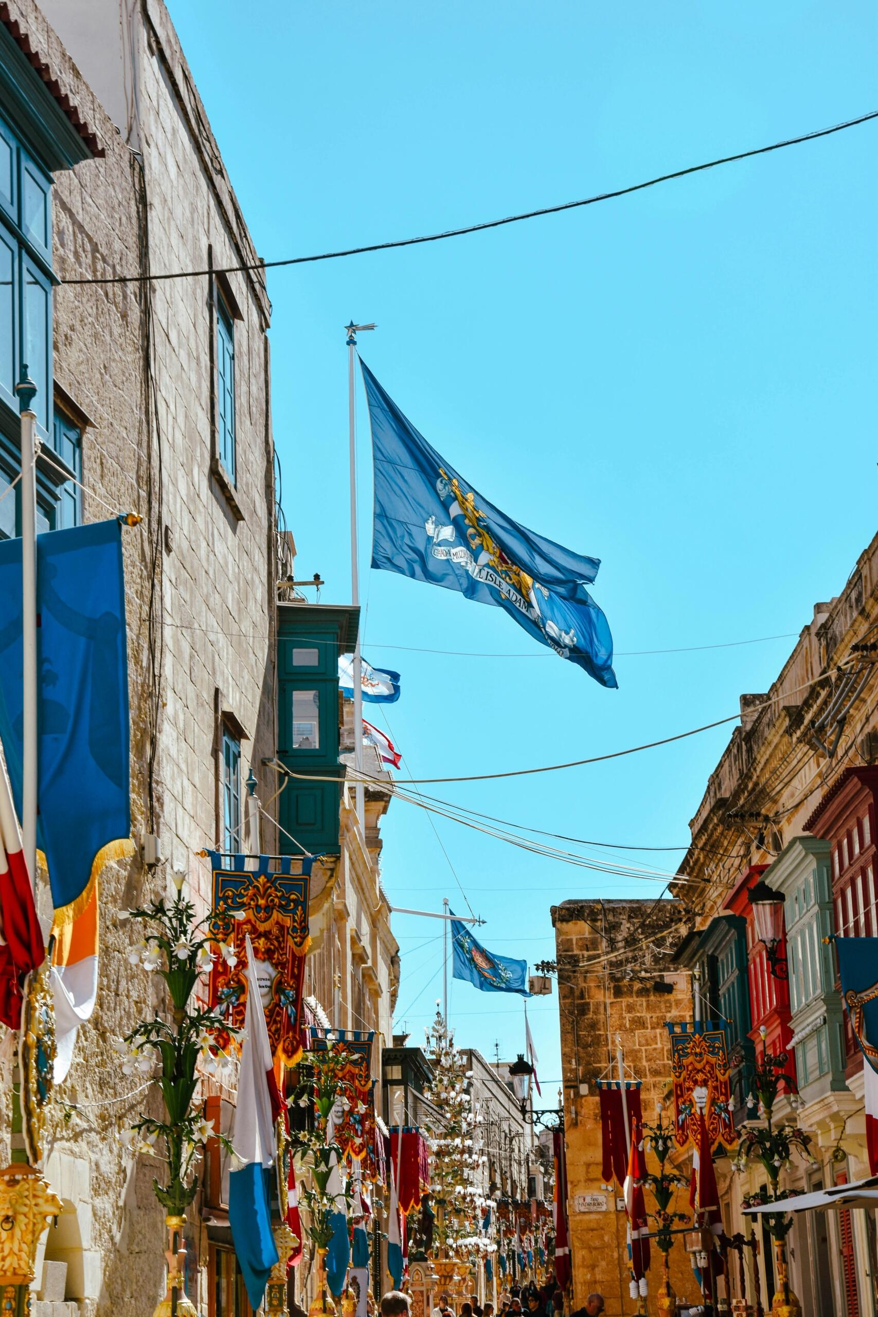 decorated Maltese village street with colourful festa flags and banners