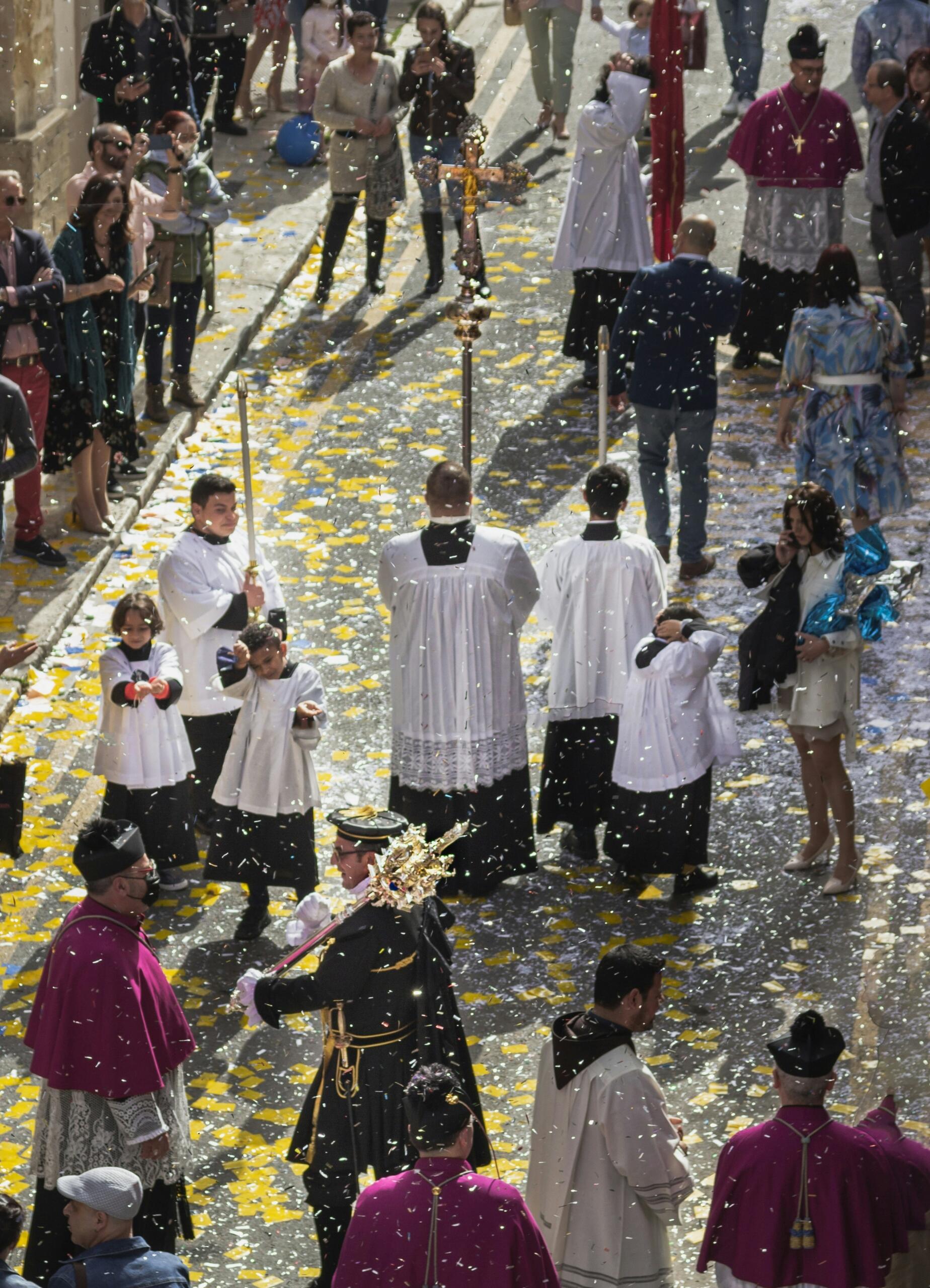 Maltese festa procession with clergy and confetti in village streets