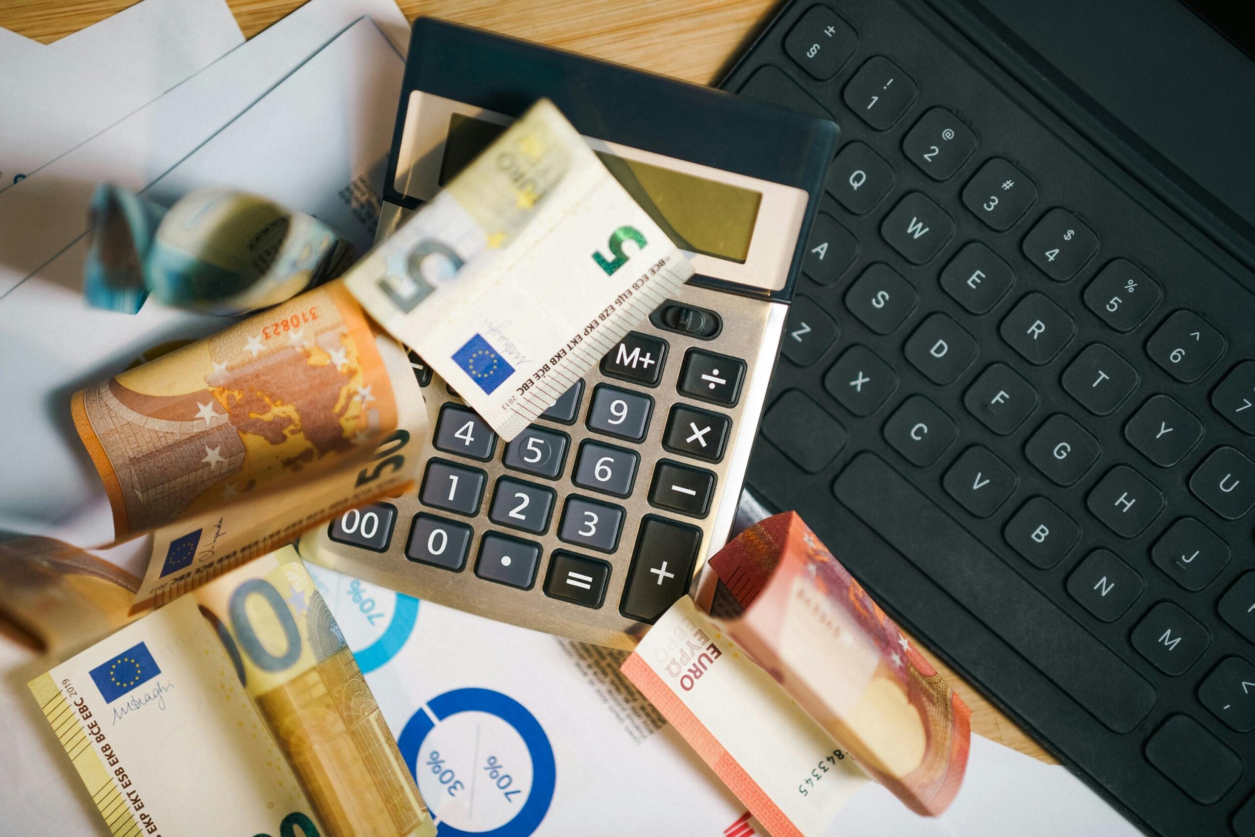 A calculator lies on top of a pile of banknotes.