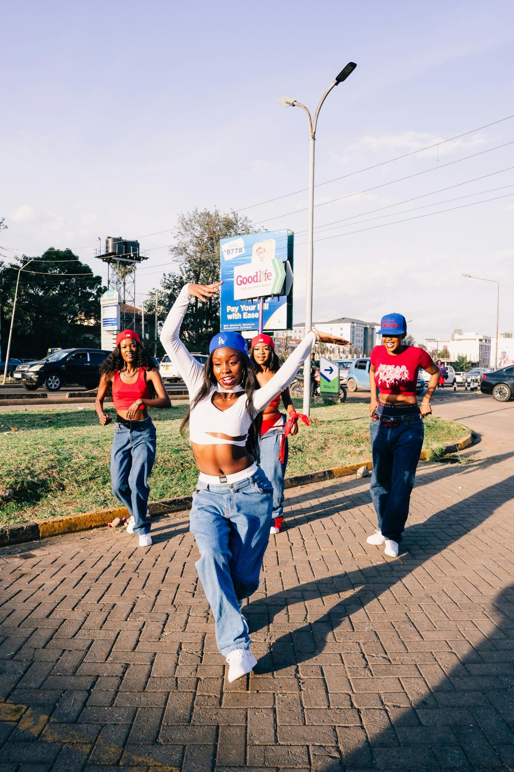 Four women dance together in baggy jeans and crop tops.