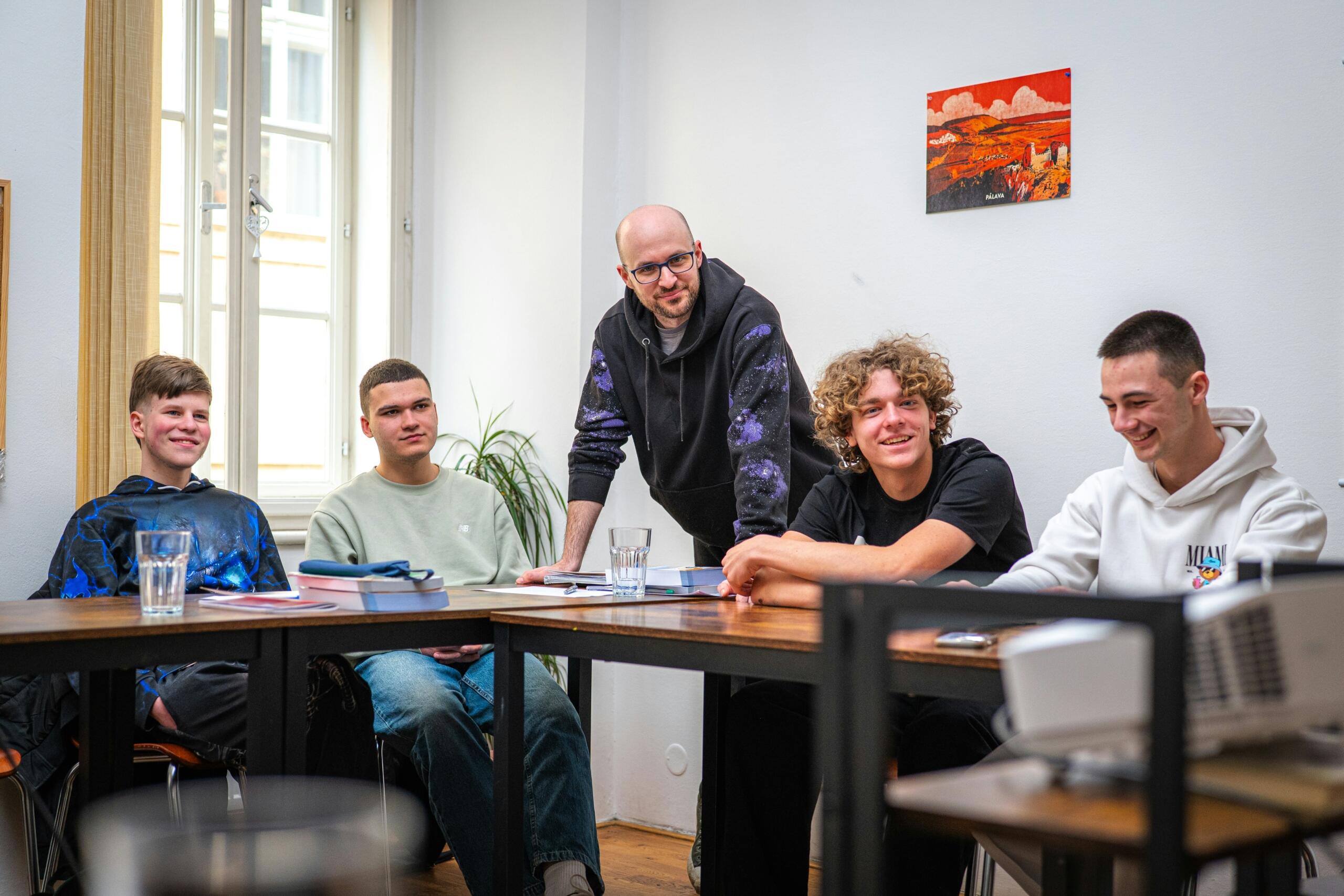 A group of young men gather around a table during a discussion.