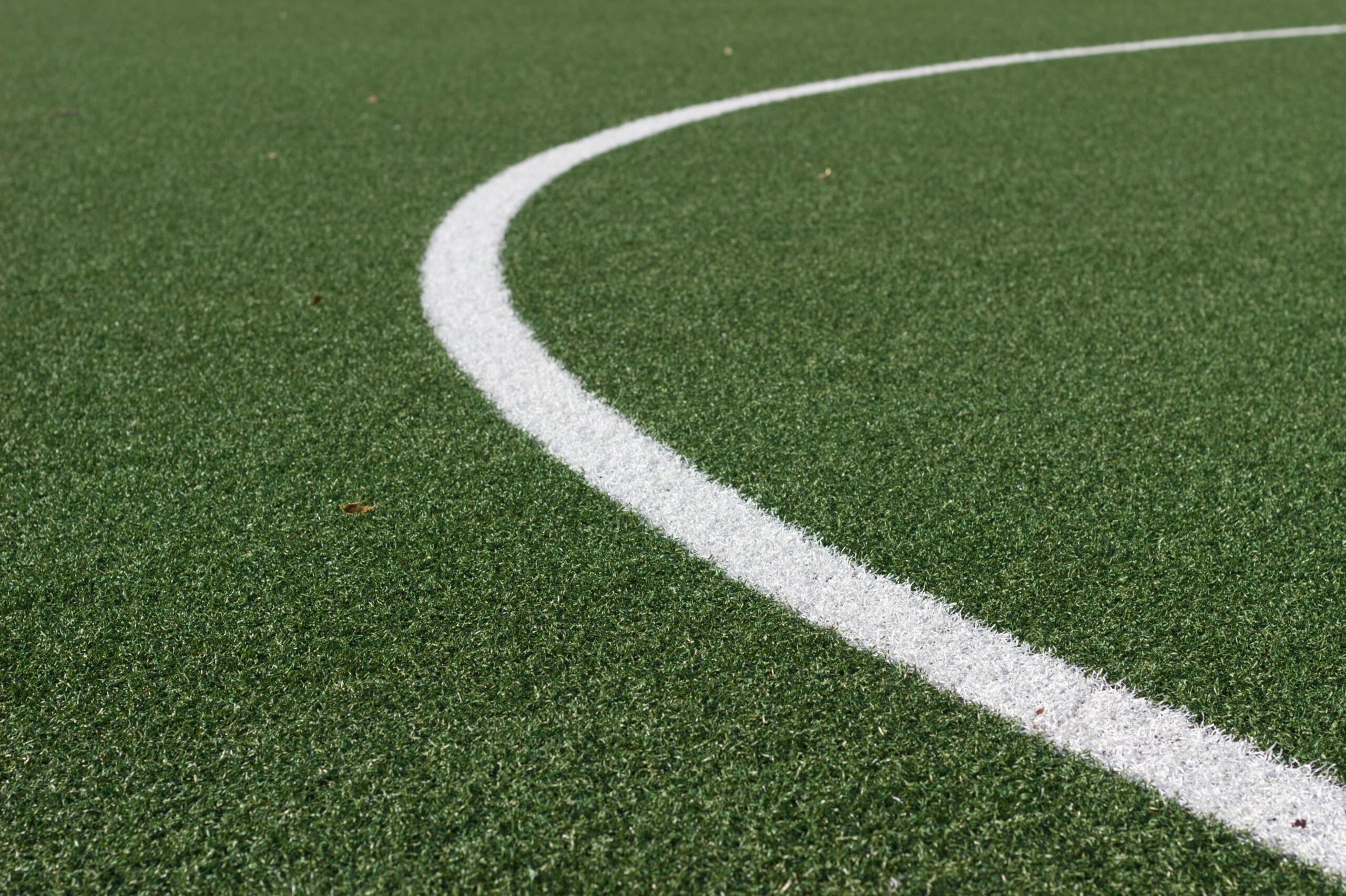 Close up of a white line marking on a green football pitch