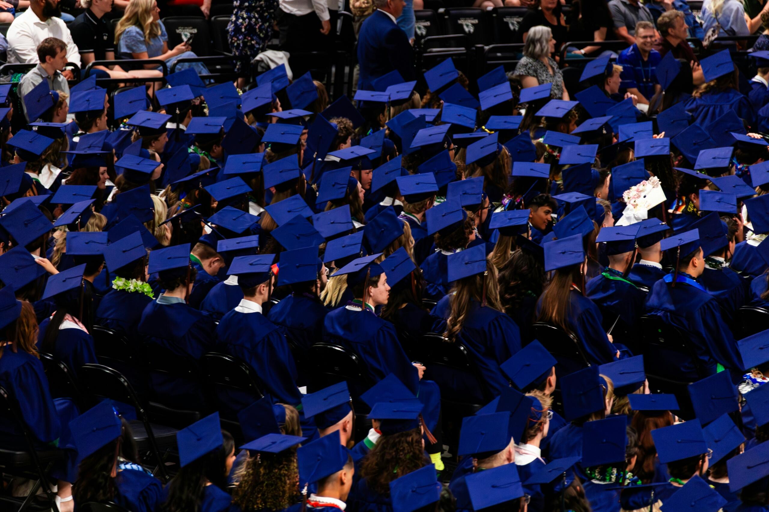 Large group of graduating students wearing blue caps and gowns at a graduation ceremony
