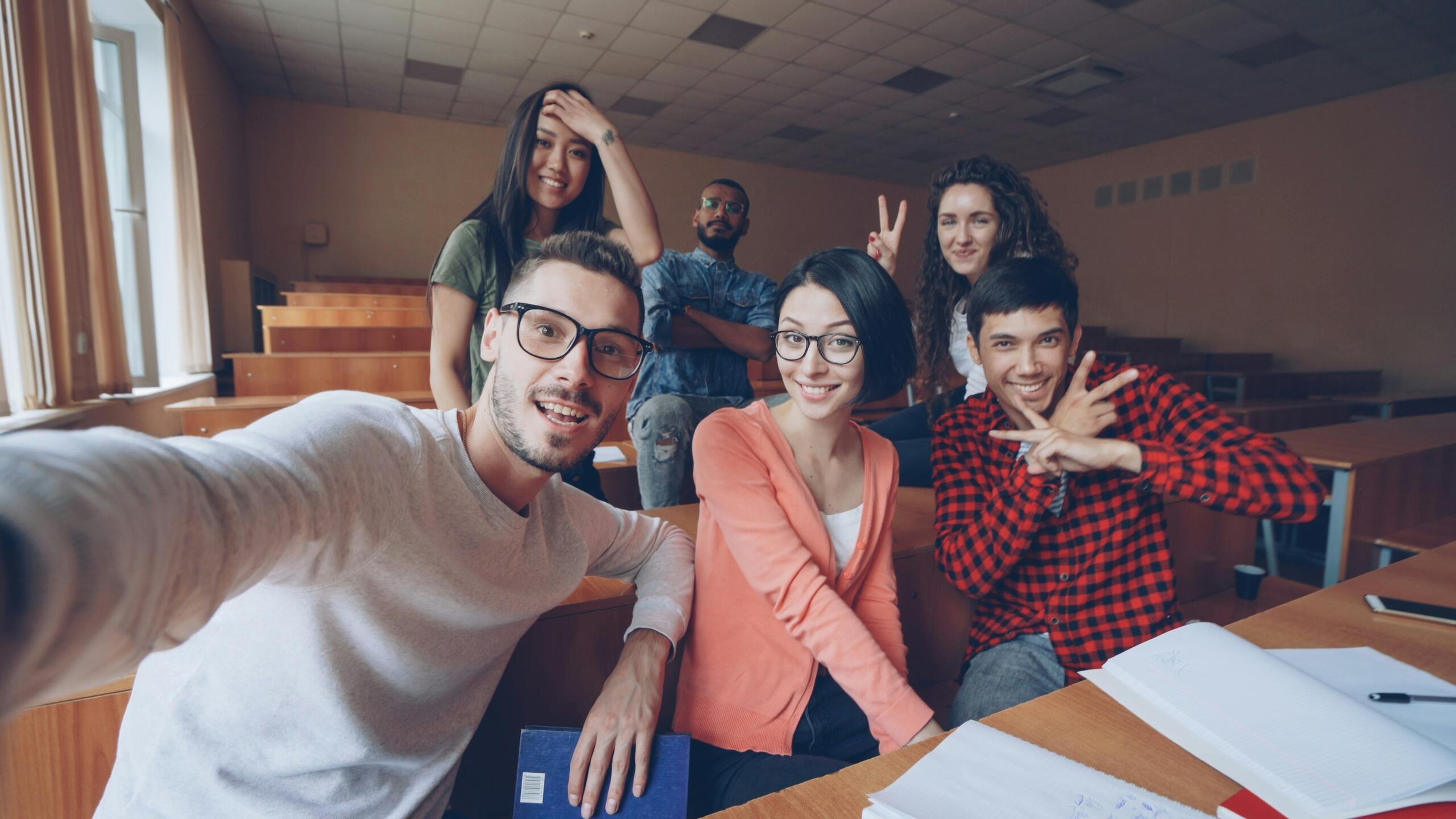 Group of international students taking a selfie together in a university lecture room