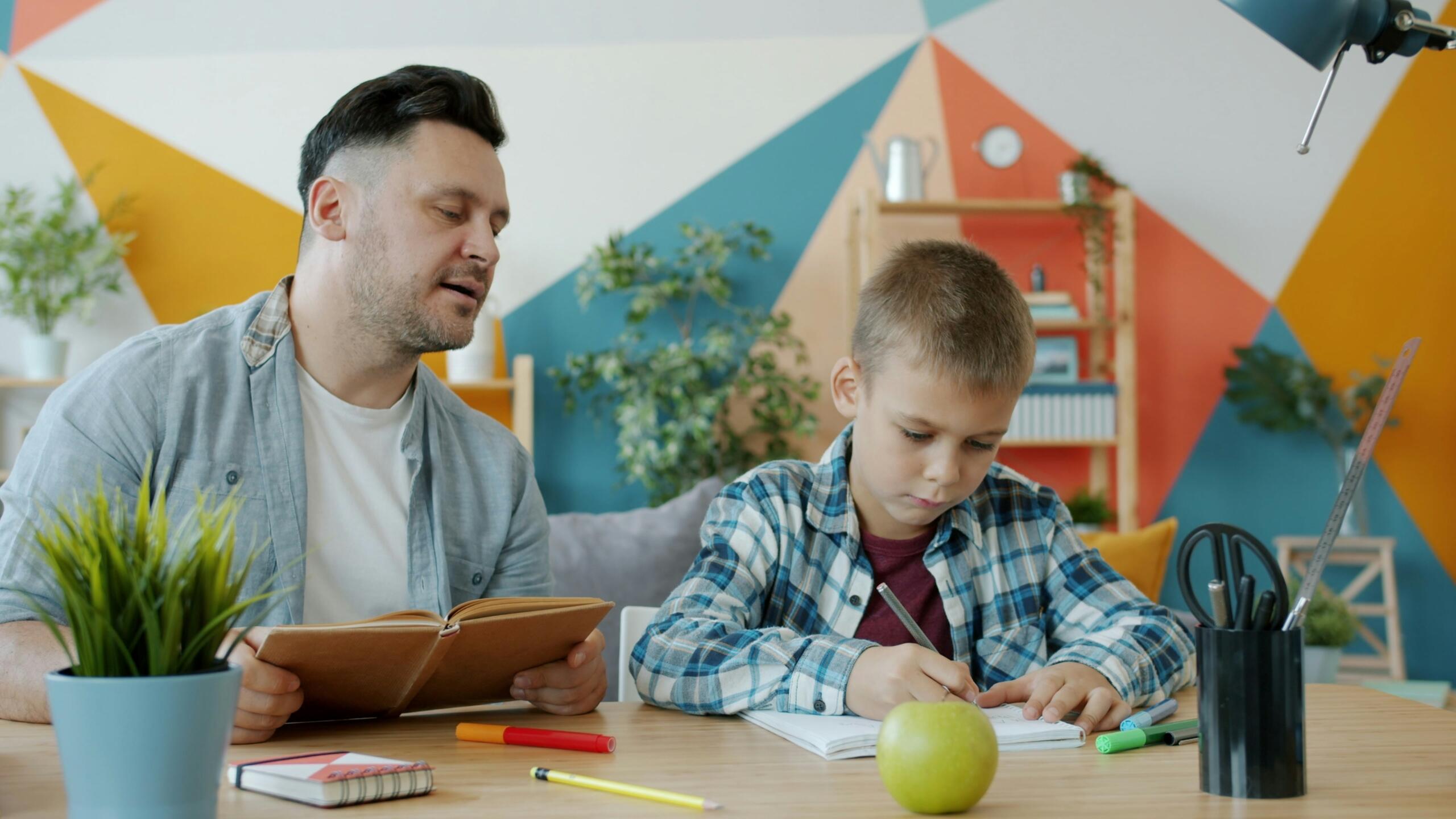 Father helping his son with homework at a desk at home