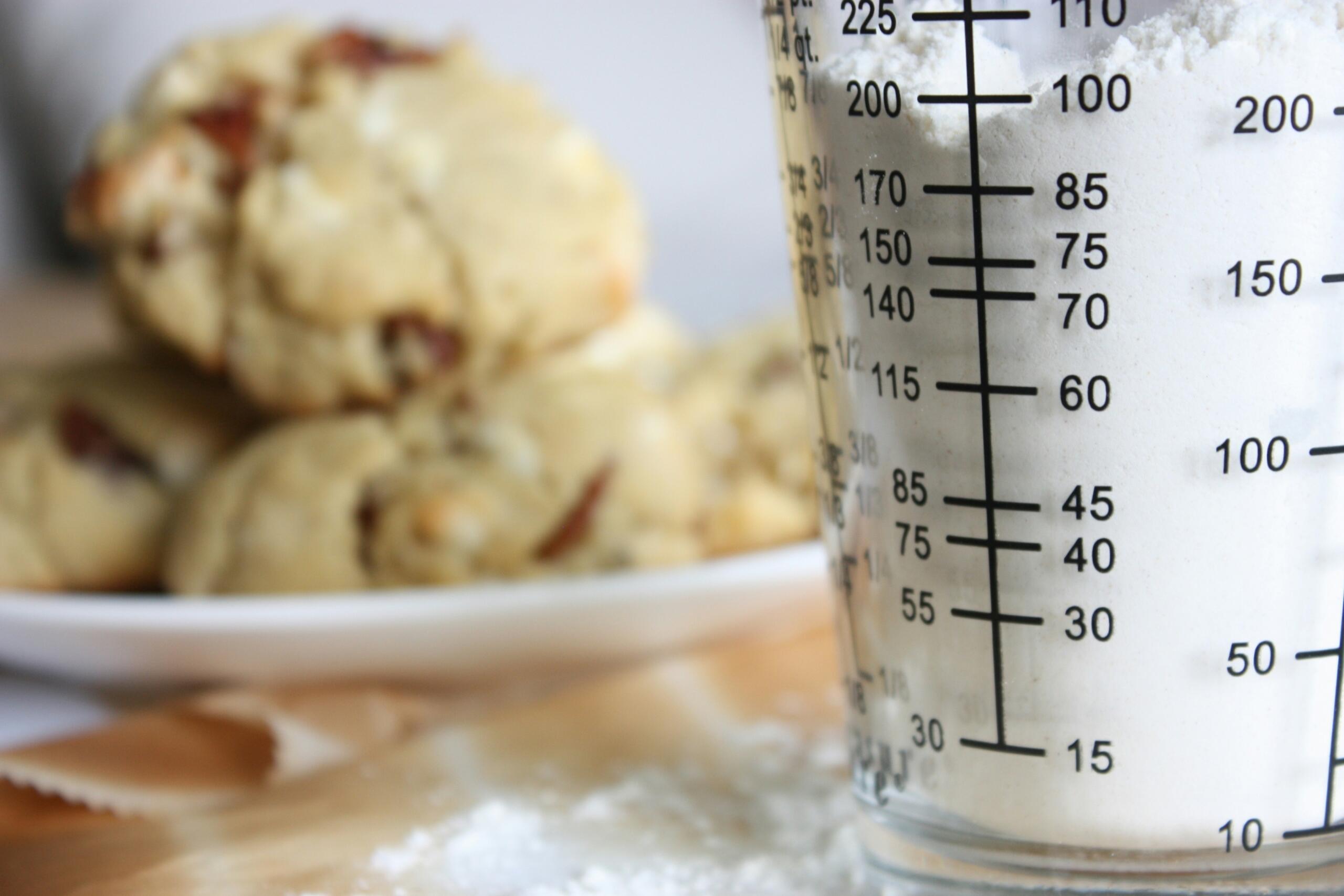Glass measuring cup filled with flour on a kitchen work surface