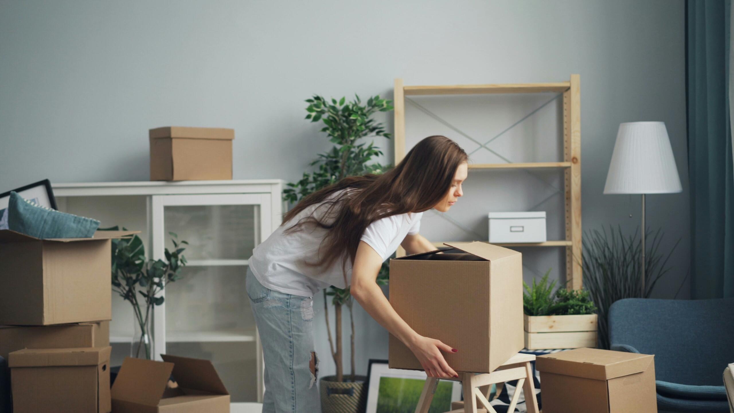 Young woman unpacking moving boxes in a new apartment