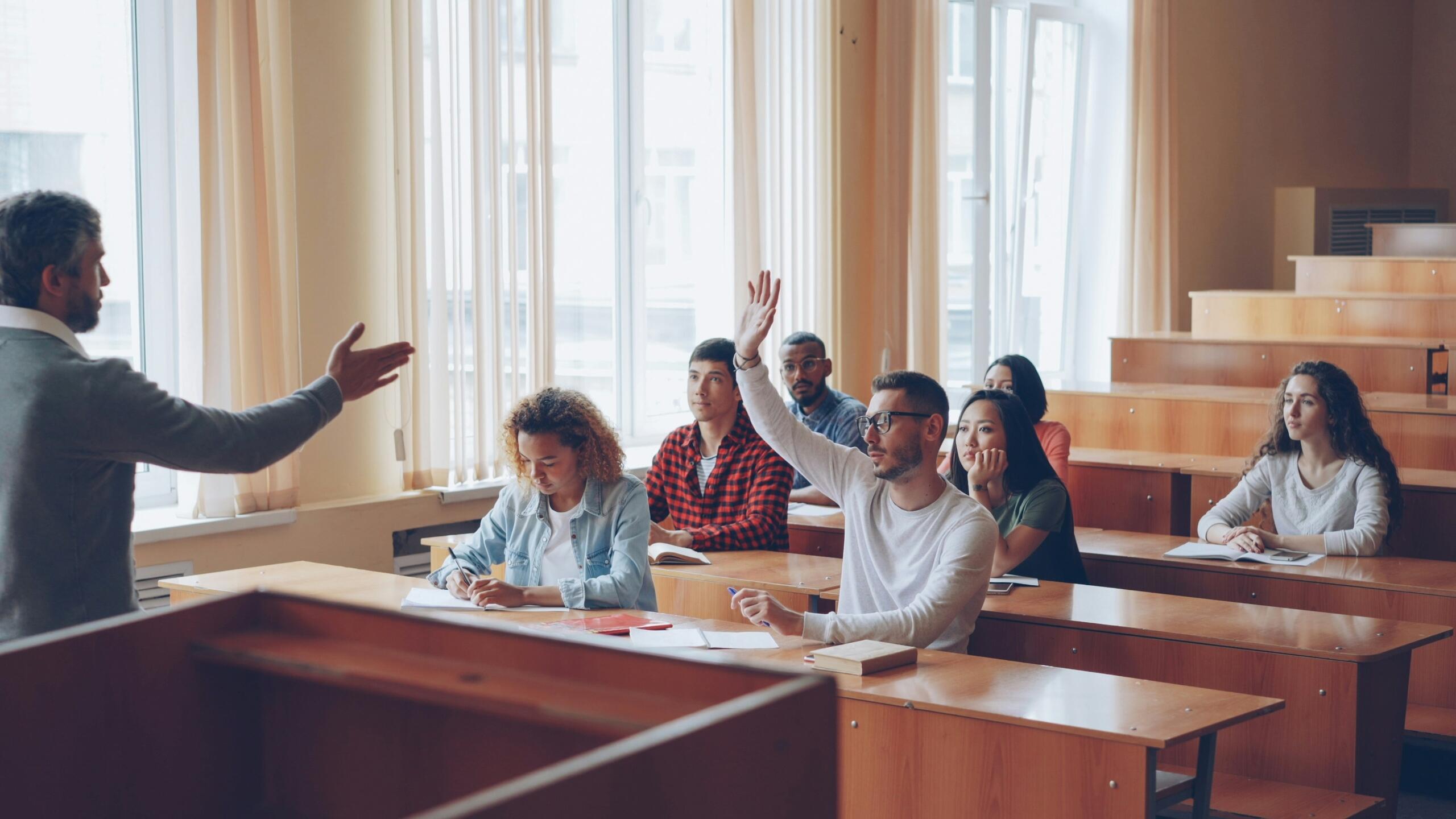 Diverse group of students in a university lecture with a lecturer at the front of the classroom