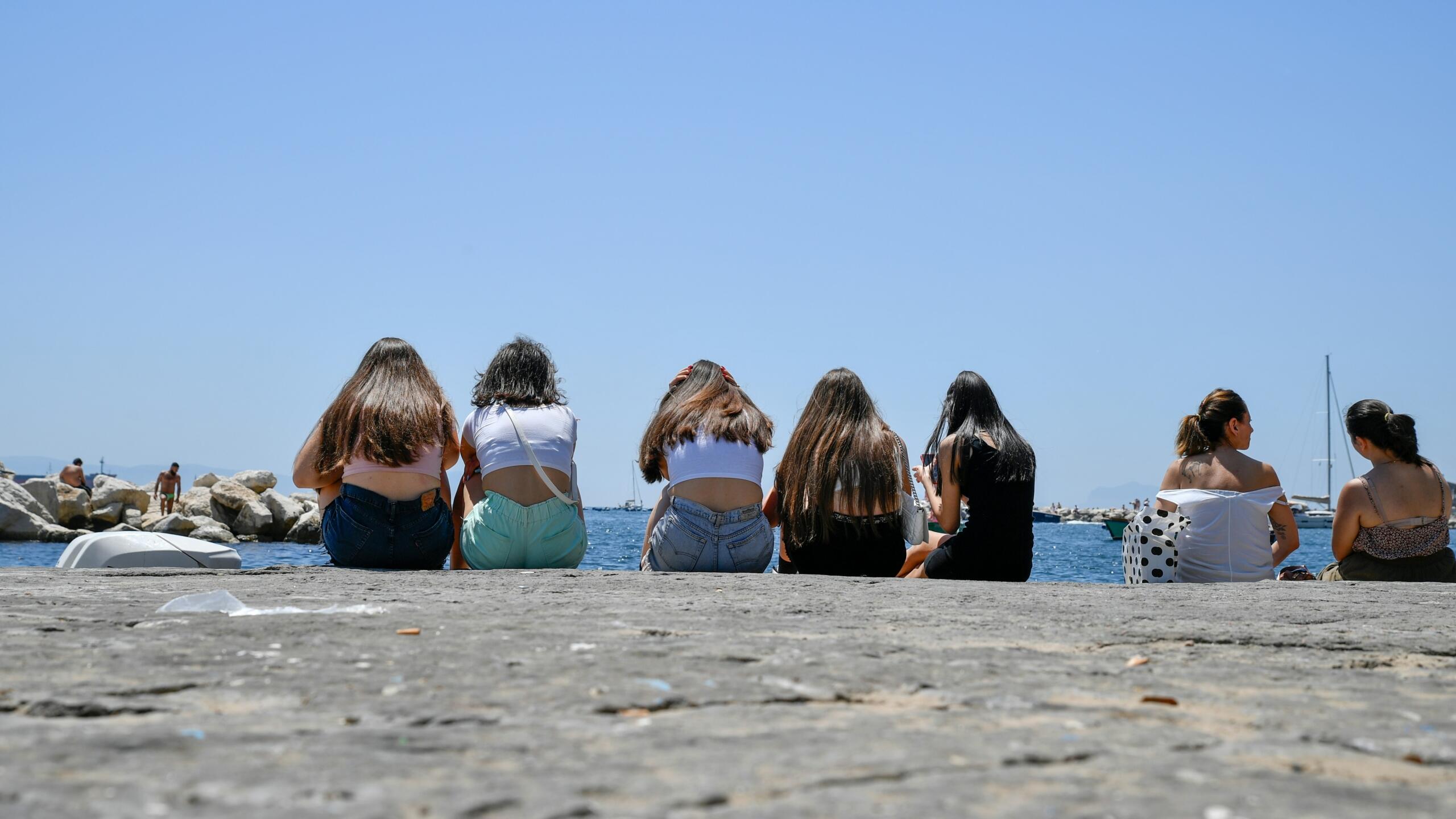 Group of young women sitting by the sea on a sunny day
