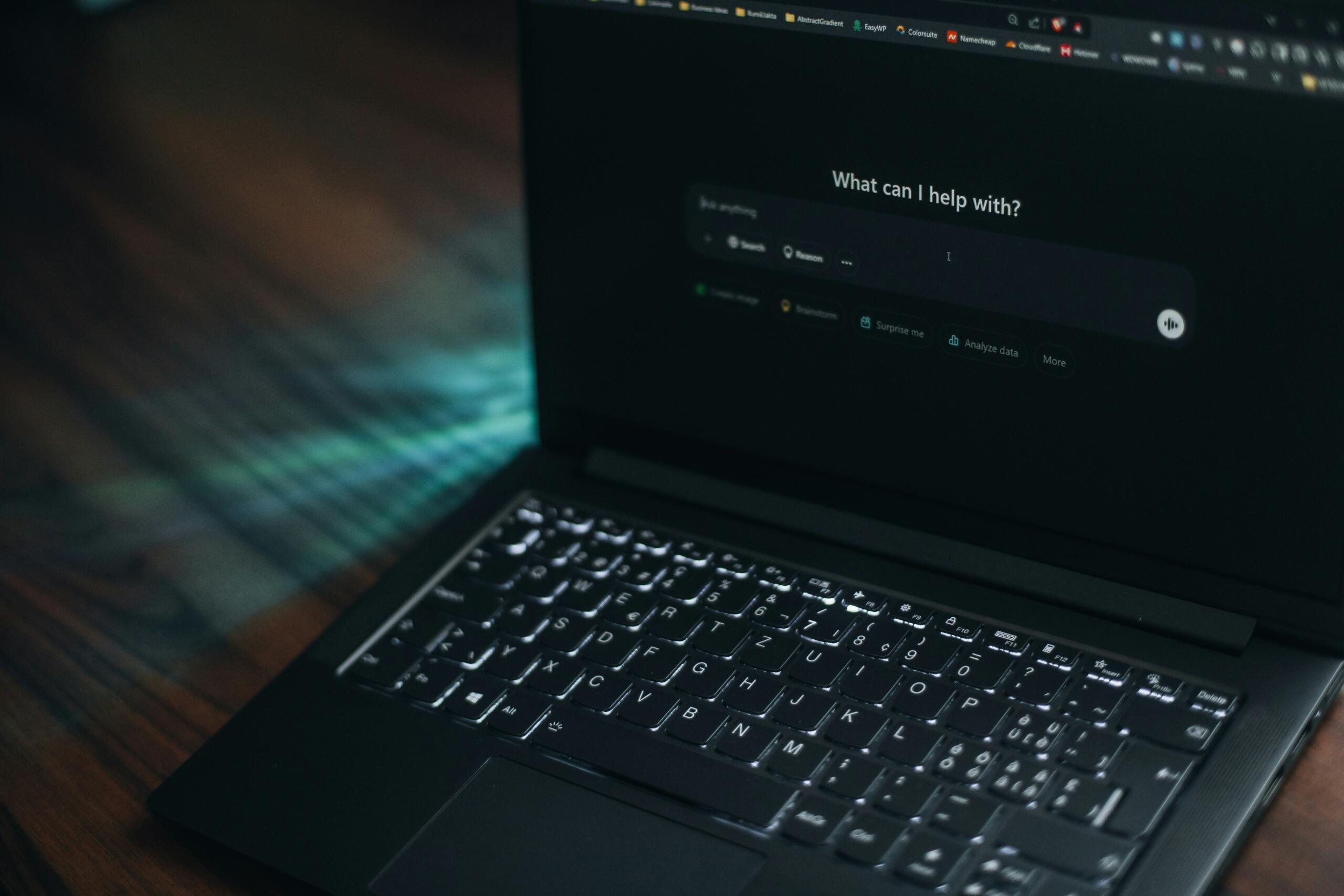A laptop displaying an AI chatbot interface on its screen in a dark room.