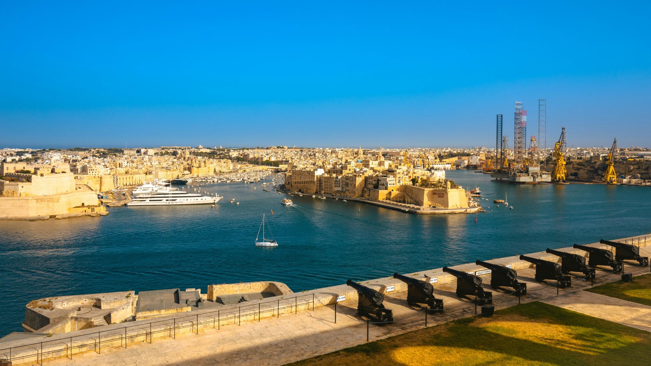 Saluting Battery cannons at the Upper Barrakka Gardens overlooking the Grand Harbour, Fort St Angelo and Senglea in Malta.