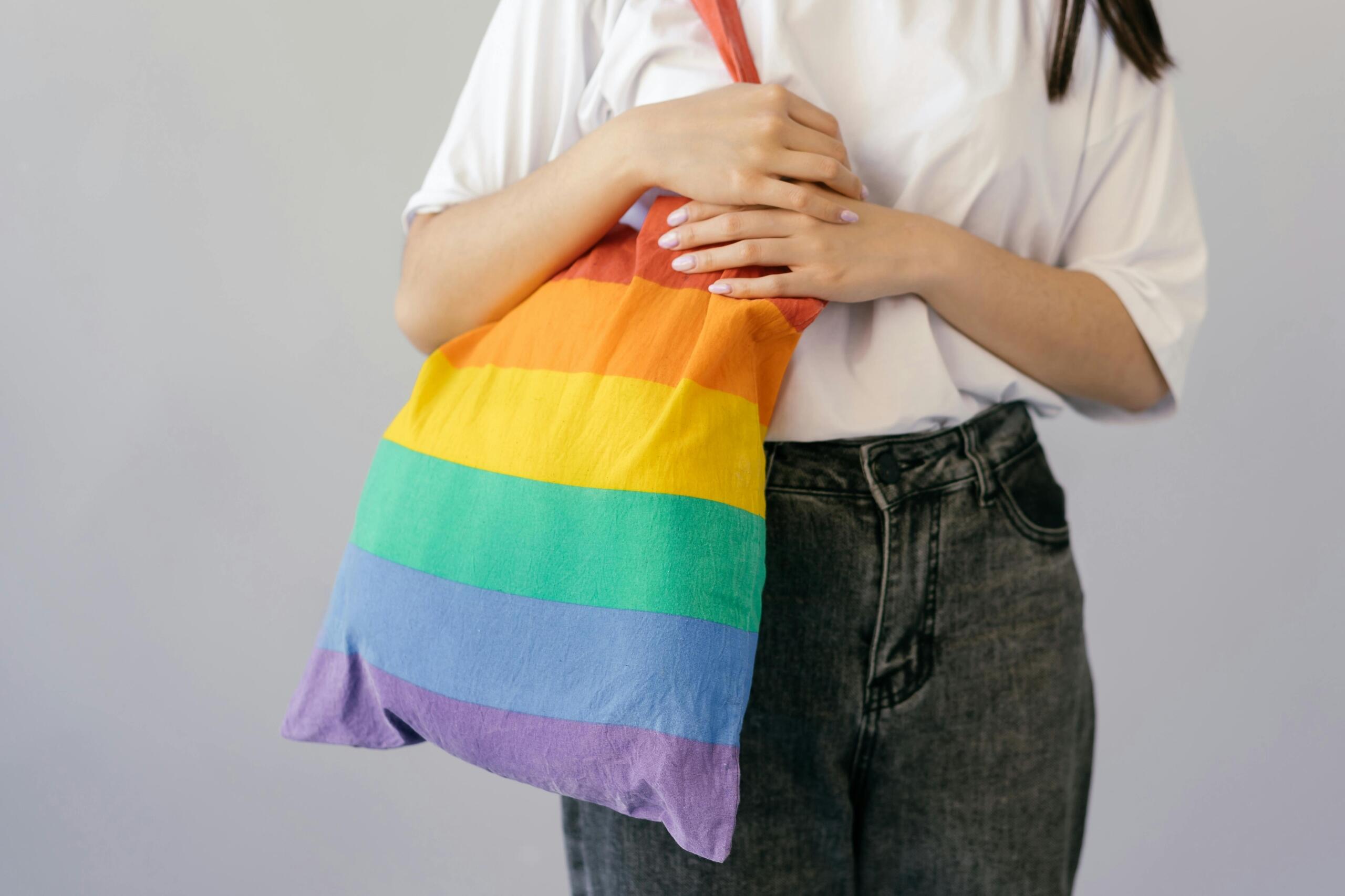 A person holding a rainbow tote bag