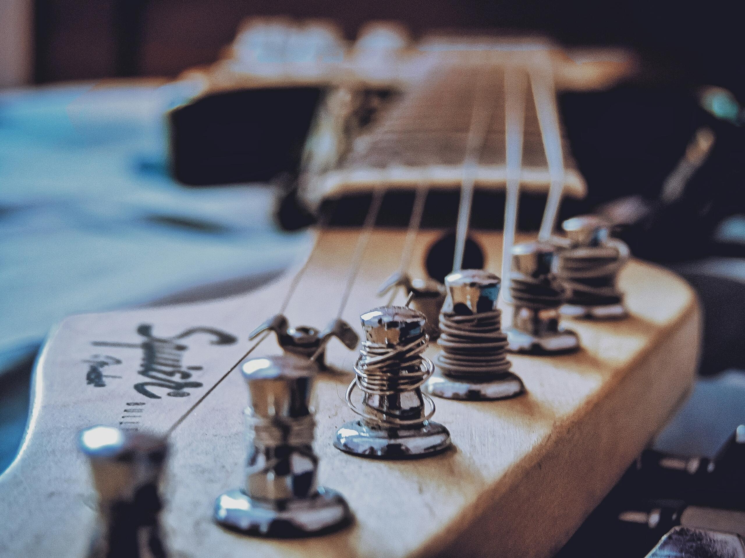 A close-up view of an electric guitar’s headstock showing tuning pegs and coiled strings in sharp detail.