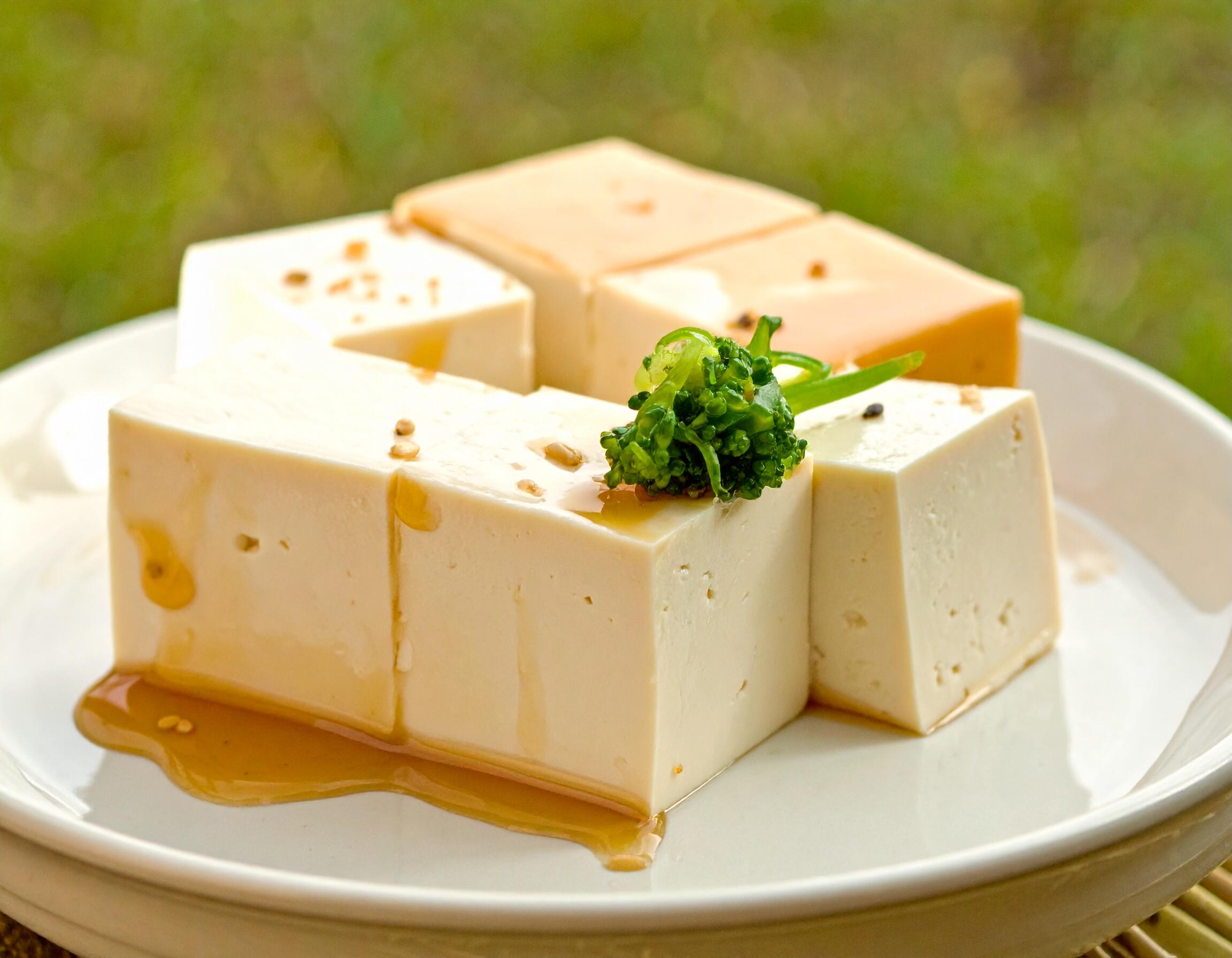 Smooth, golden-glazed tofu cubes topped with fresh greens, showcasing a delicious and protein-rich staple of vegan cooking.