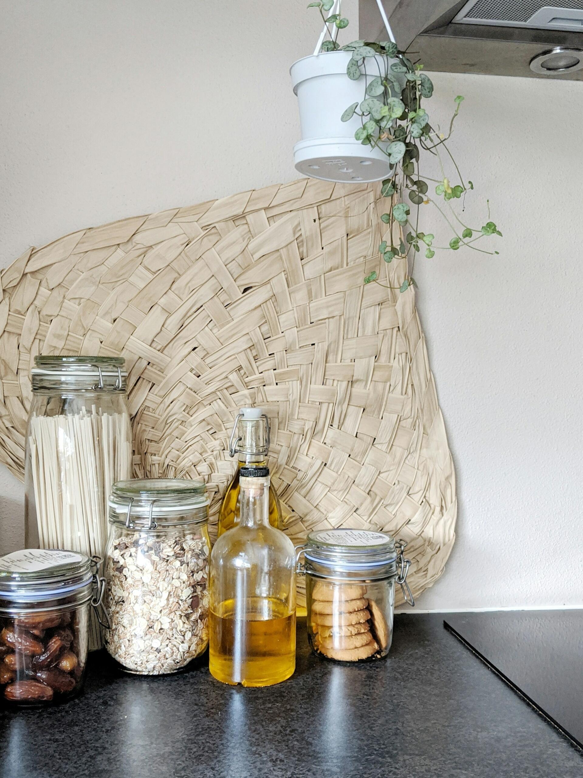Clear glass bottles, jars, and pottery with white flowers arranged on a grey shelf