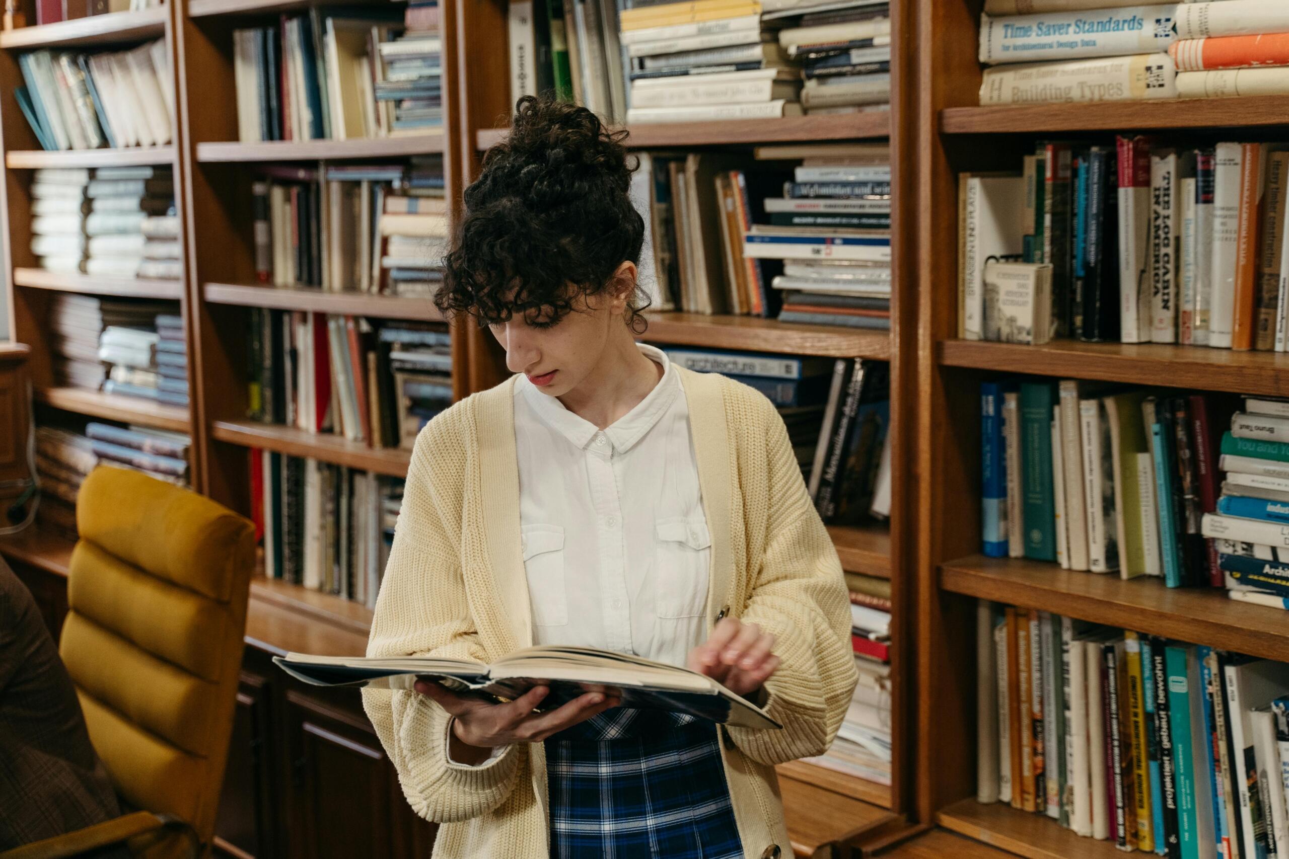 A woman in a yellow sweater reading a book