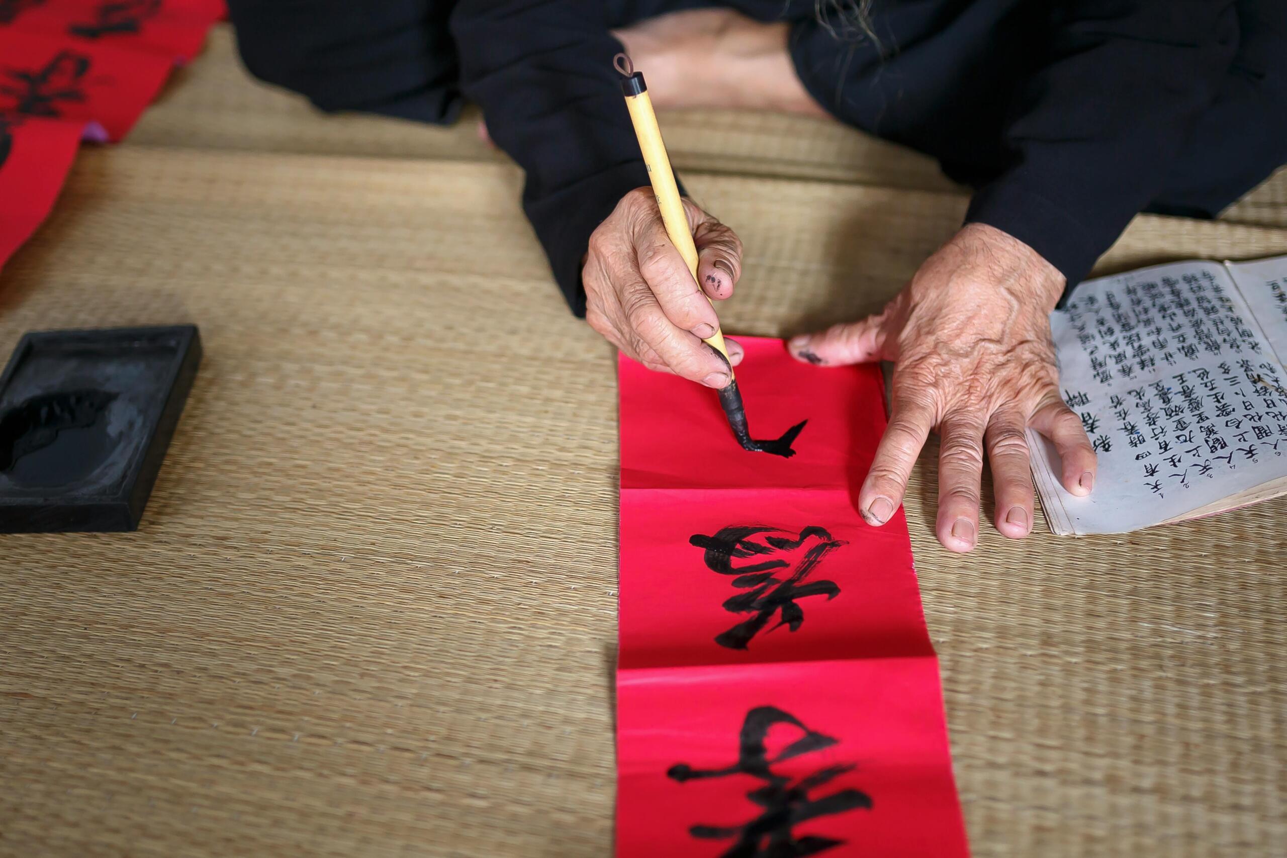 Person writing Chinese calligraphy on paper