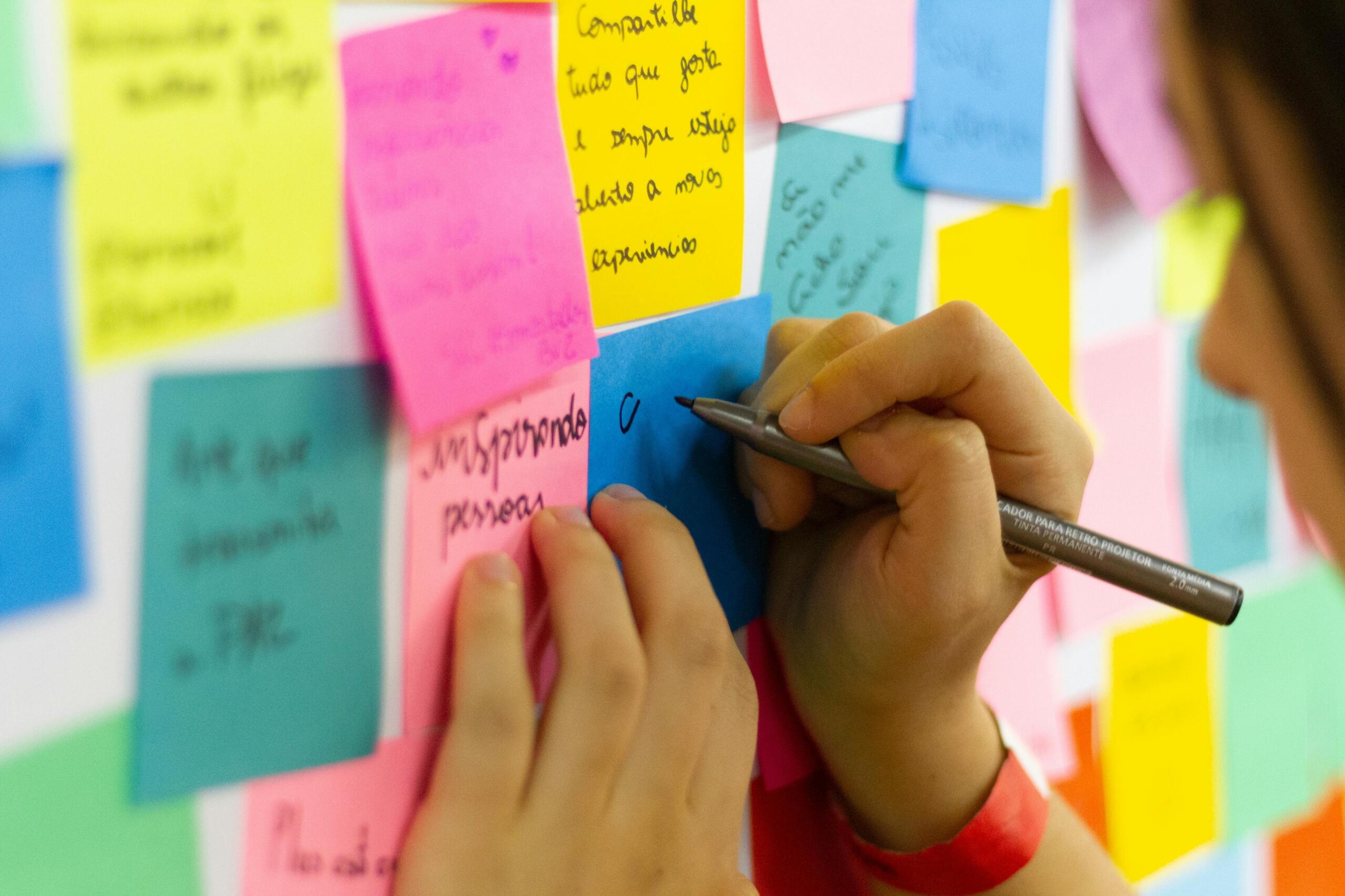 Person writing on sticky notes stuck to a board