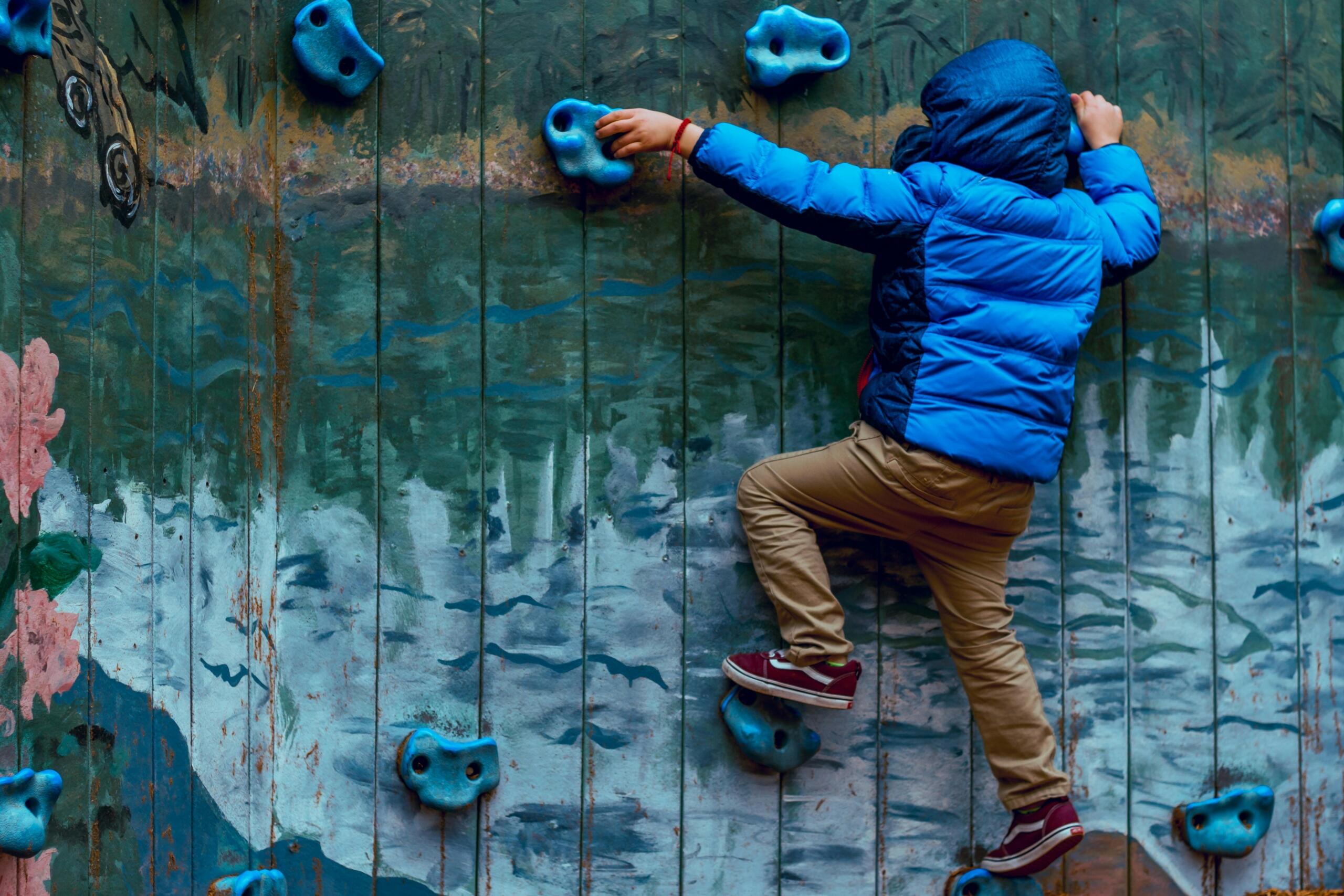 Boy in blue parka wall climbing