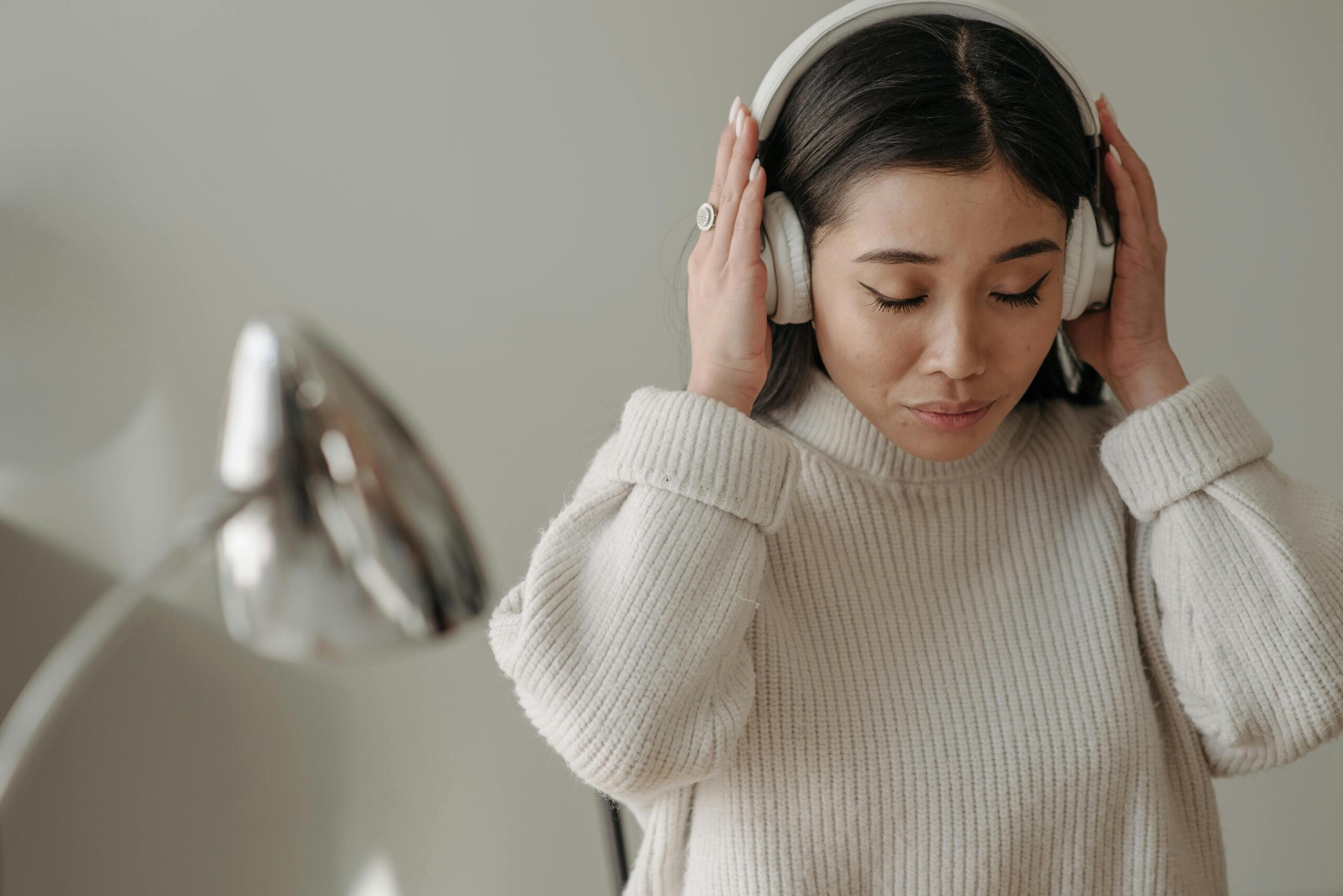 A woman in a white sweater wearing headphones