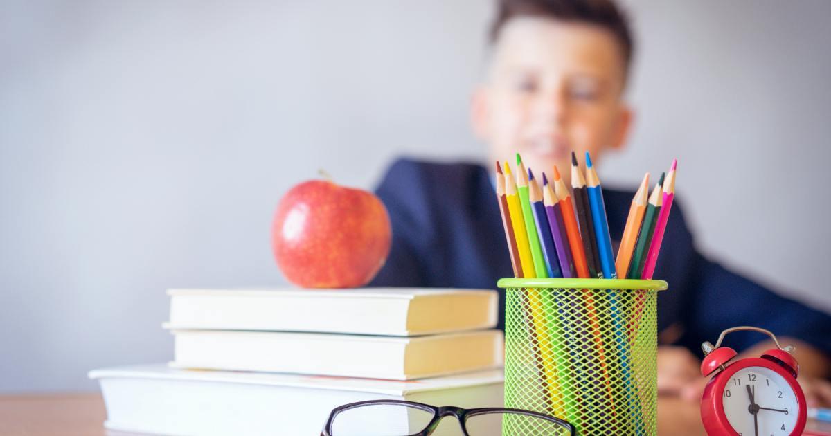 a boy looking at a stack of books and an apple