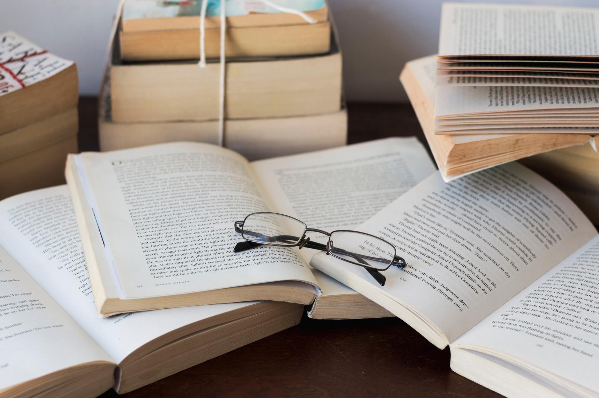 A collection of books stacked together, featuring a pair of glasses placed on top, indicating a scholarly theme.