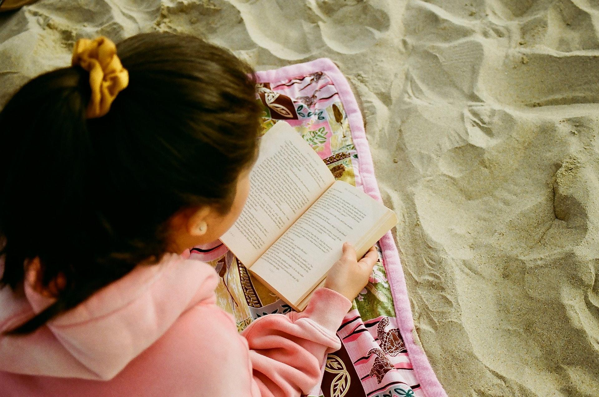 girl reading a book at the beach
