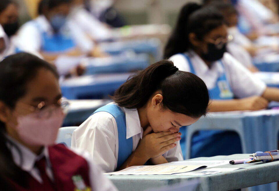Student in school uniform concentrating on exam at desk