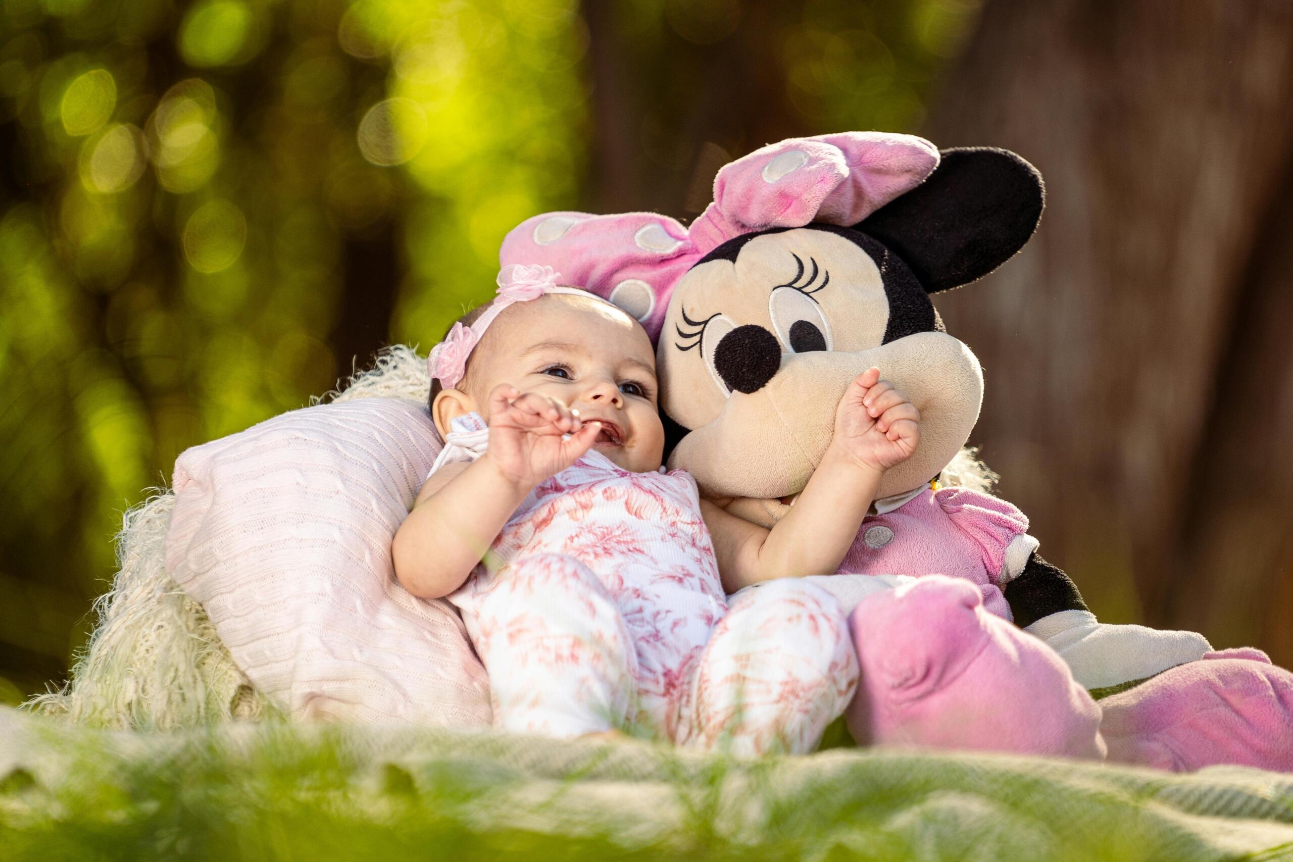 Baby lying with Minnie Mouse plushie