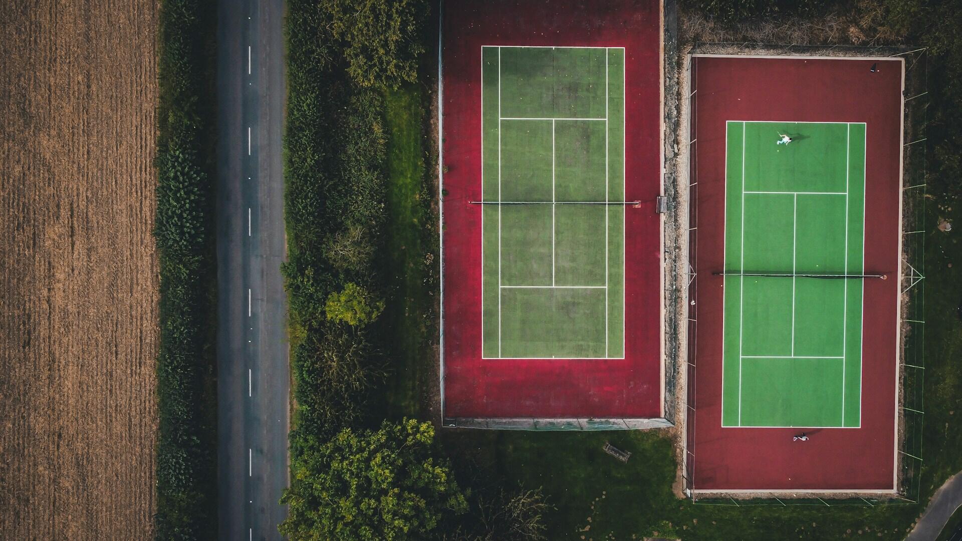 An aerial view of two tennis courts in the middle of a field. 