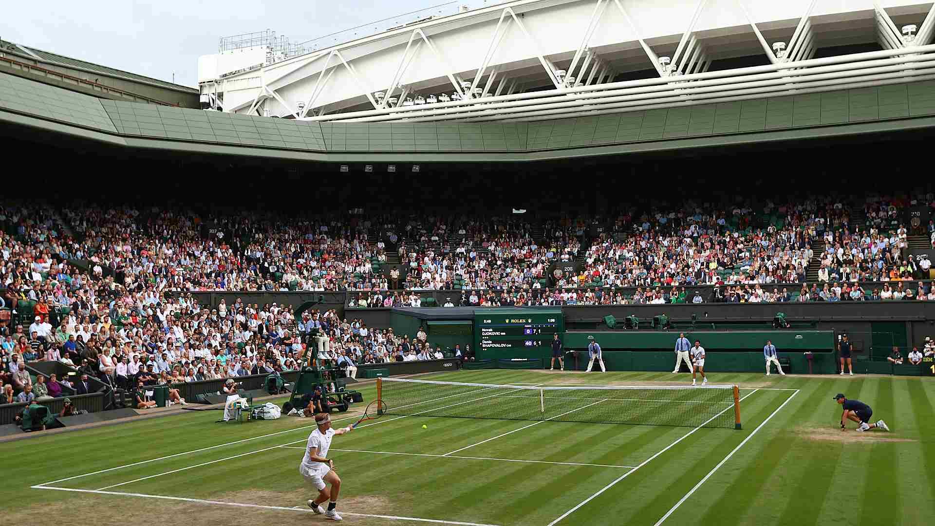Tennis match on Wimbledon with crowd watching.
