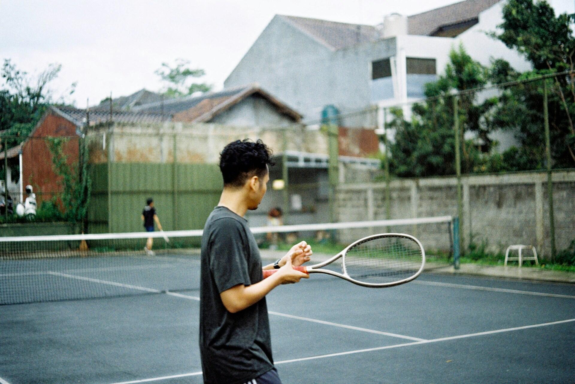 A man holding a tennis racquet on a tennis court. 