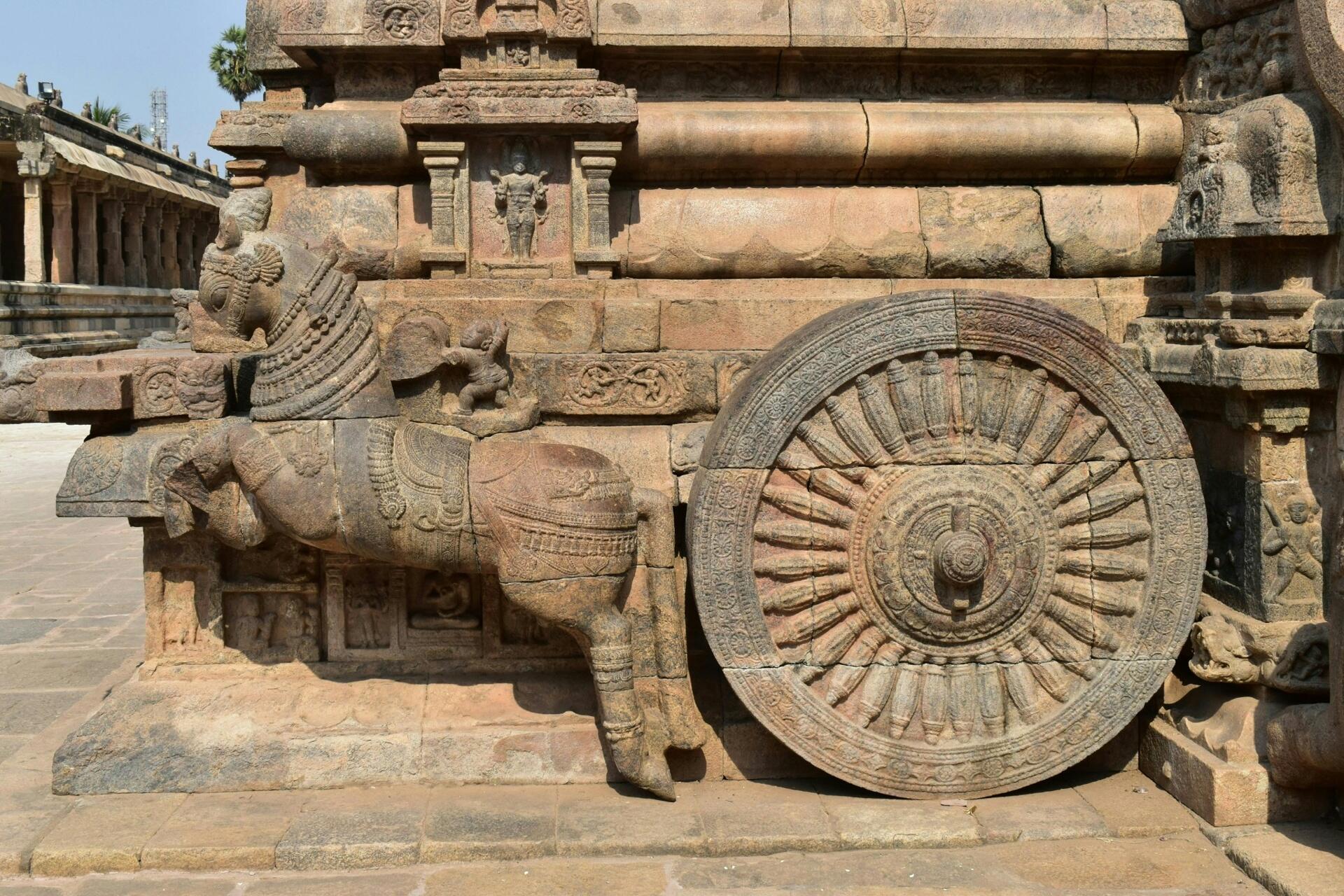 Ancient stone chariot wheel and carved horse sculpture at a historic Tamil temple complex showcasing traditional South Indian architectural craftsmanship.