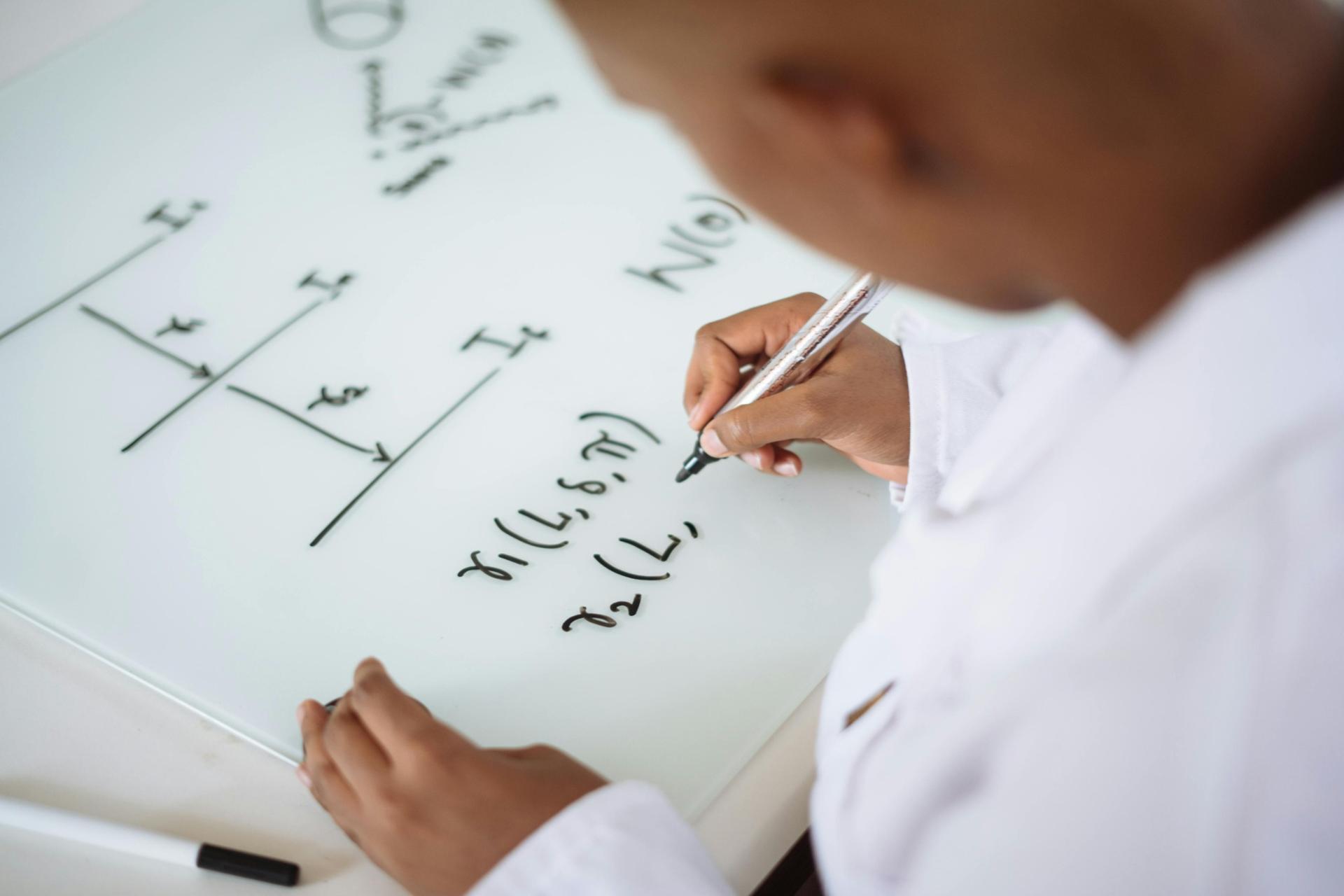 Student writing physics equations and solving problems on a board, representing calculation and analytical thinking in SPM Physics.