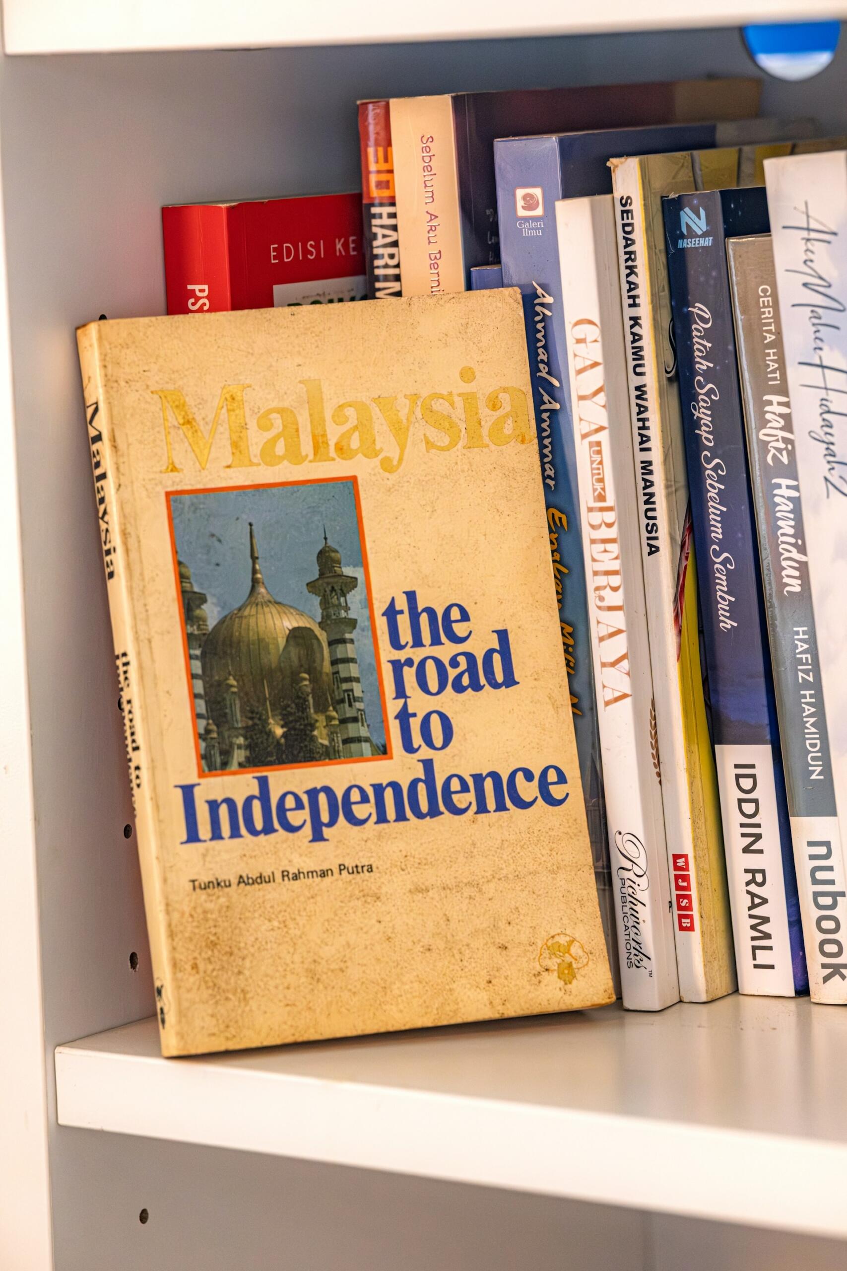 A book titled Malaysia the road to independence on a book shelf.