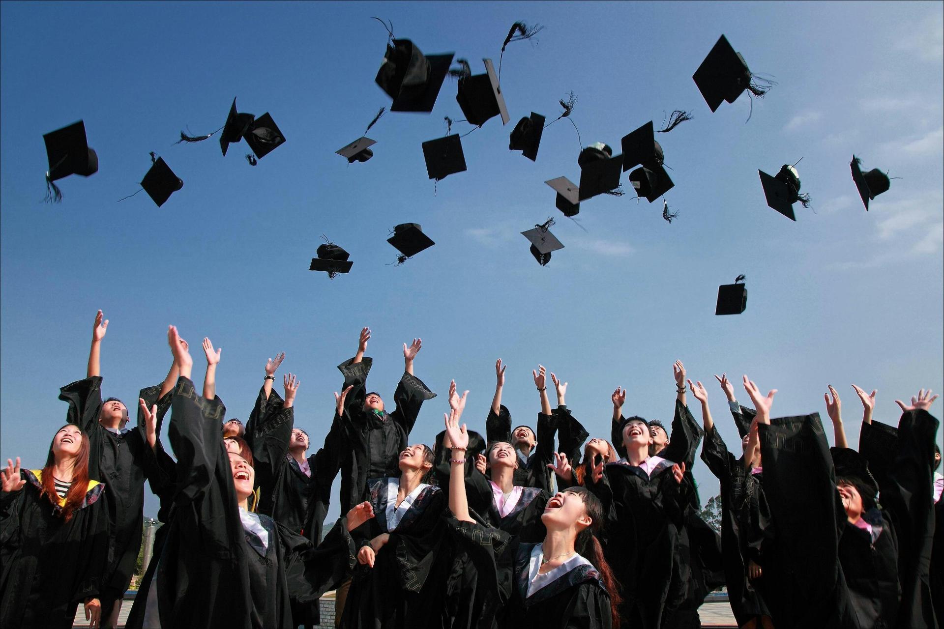 students celebrating graduation by throwing caps in the air symbolising academic success after exams 