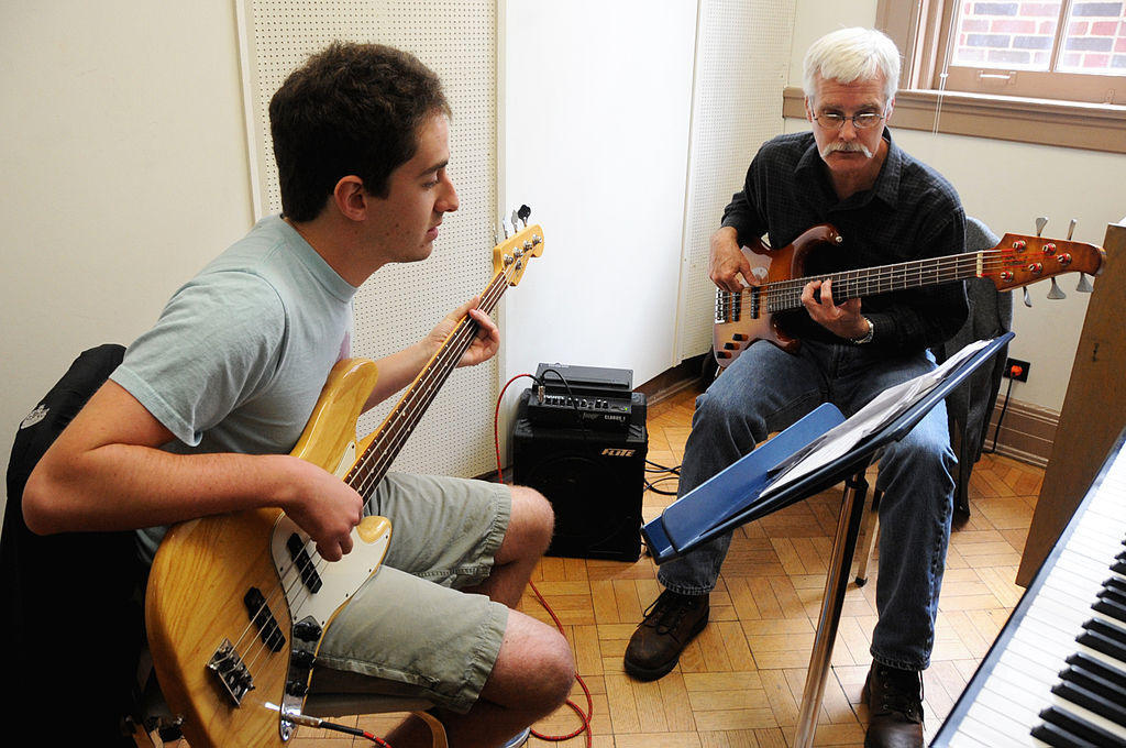 A guitar teacher and student play together.