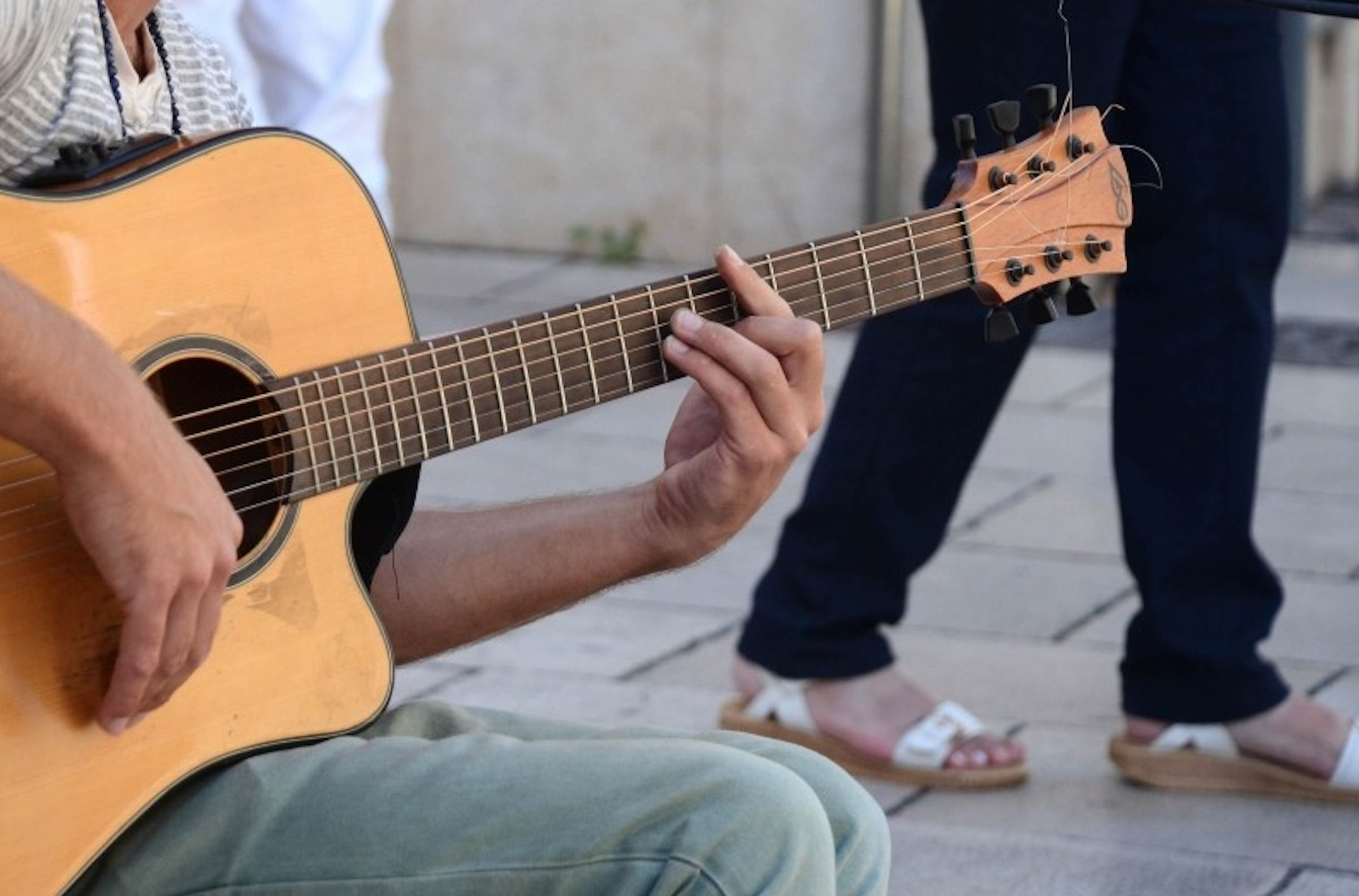 A man busks with an acoustic guitar