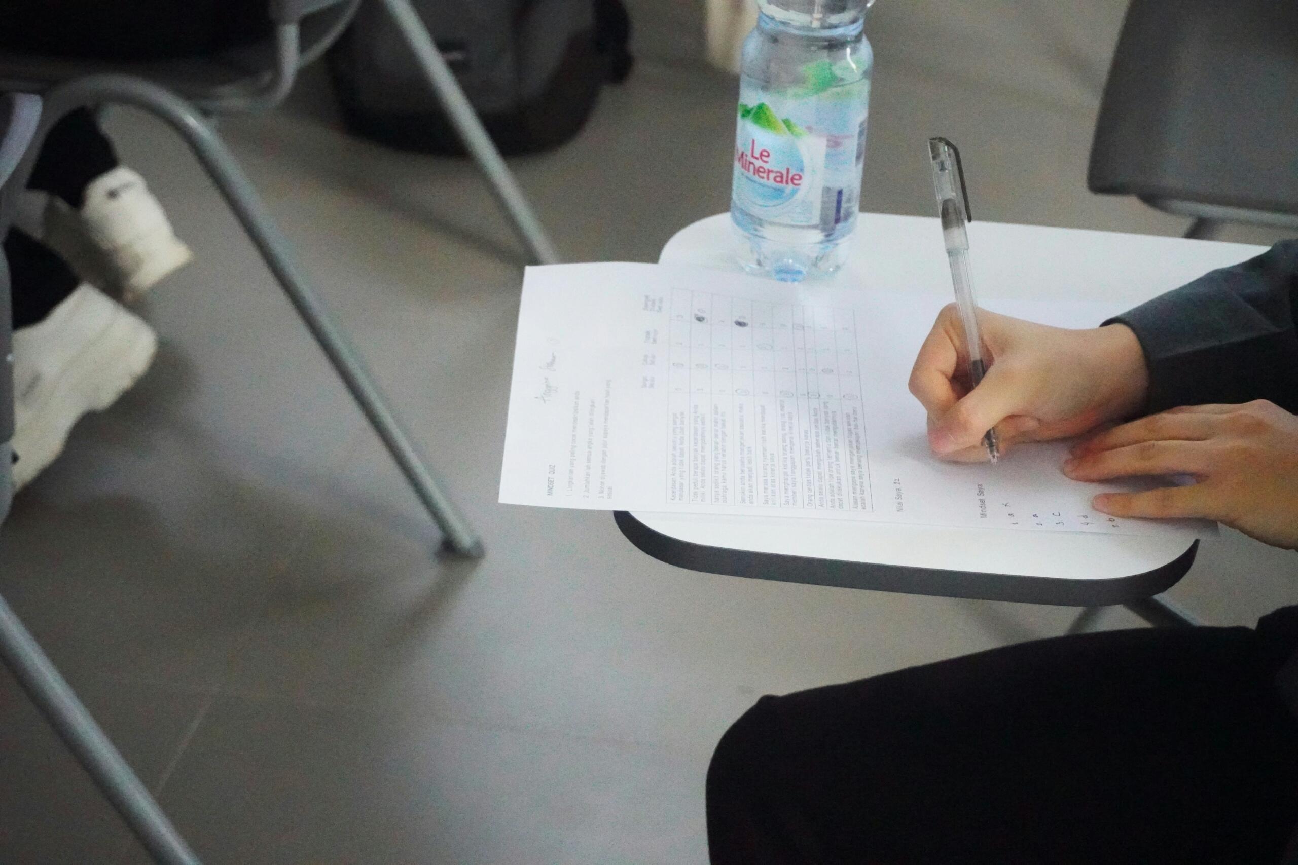 A student writing answers on an examination paper at a desk