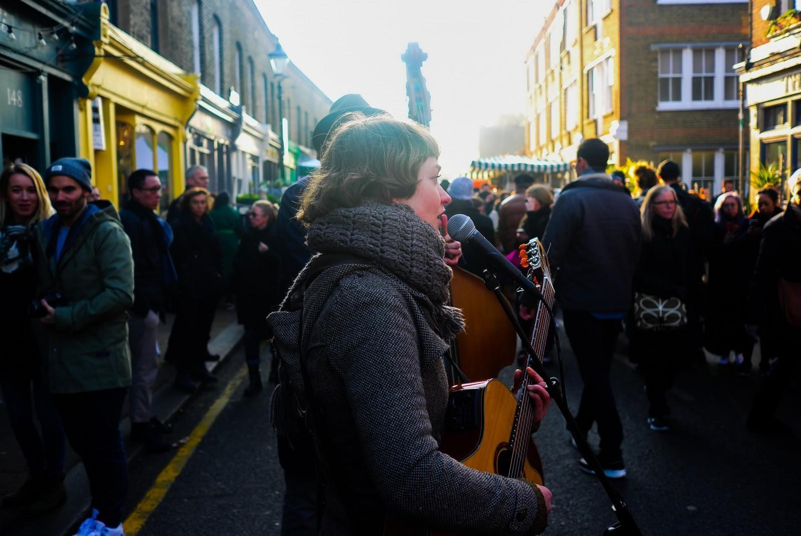 A woman busking with a guitar in a busy street