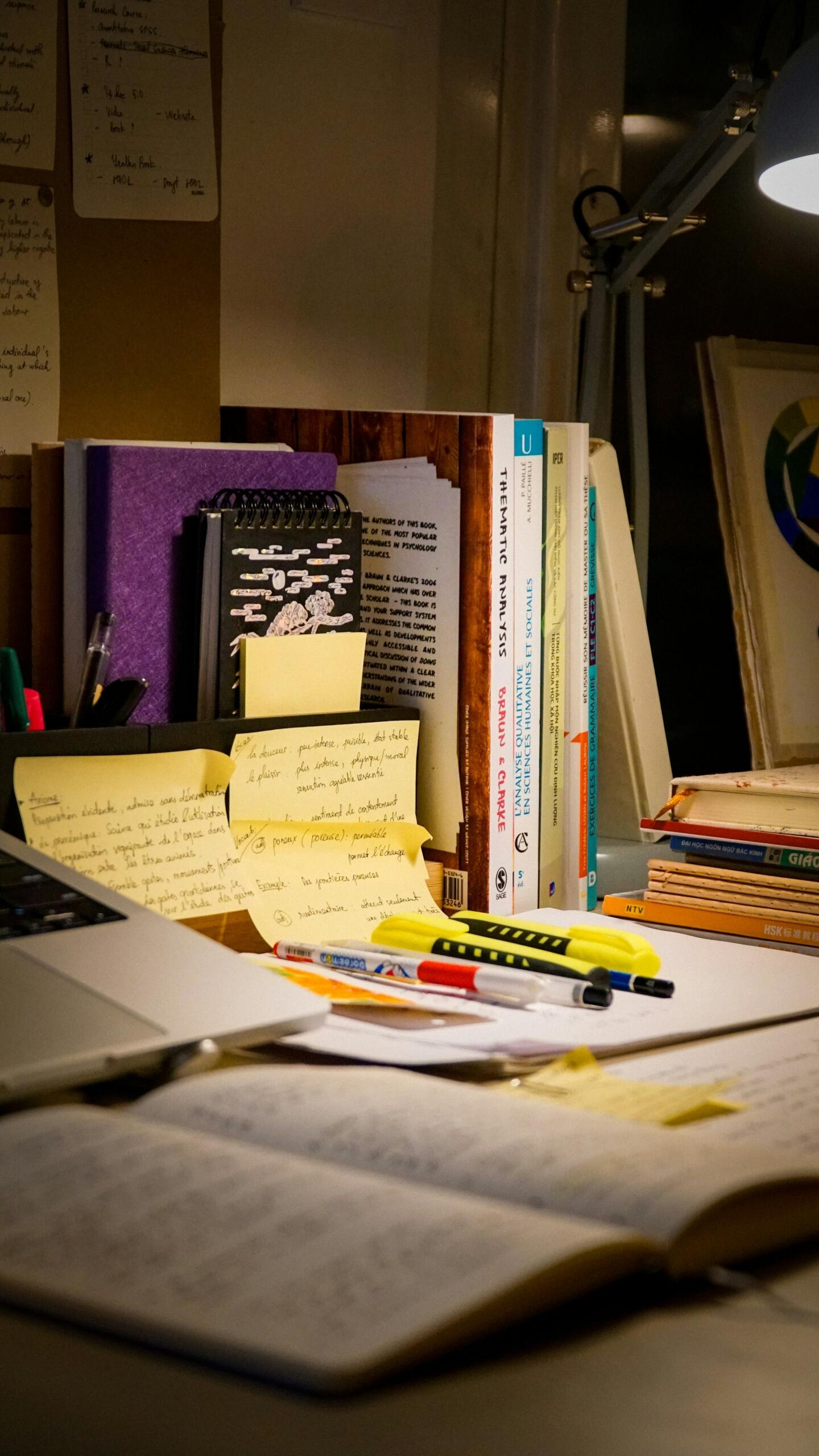 A study desk with an open book, handwritten notes and stationery