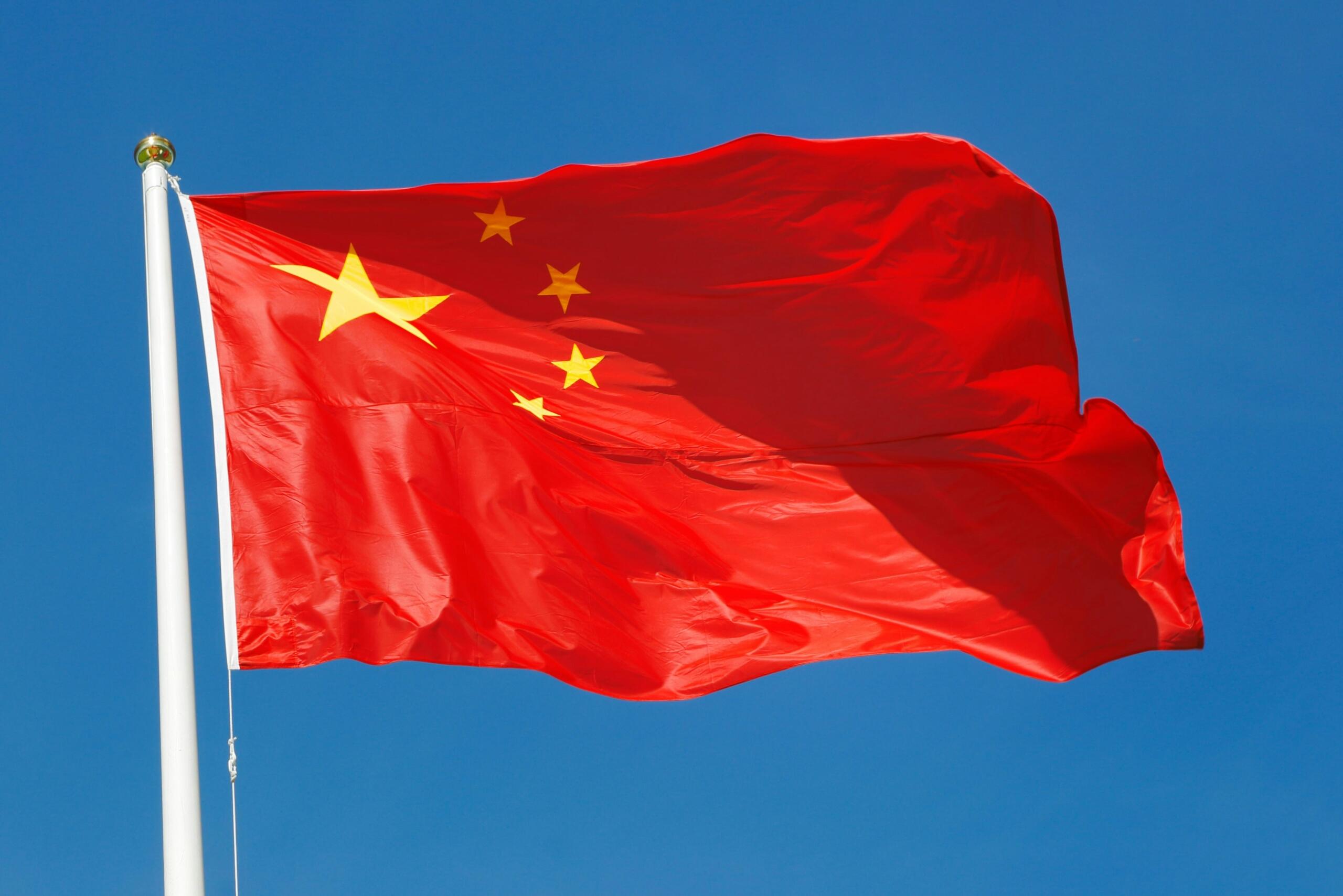 The flag of China set against a blue sky.